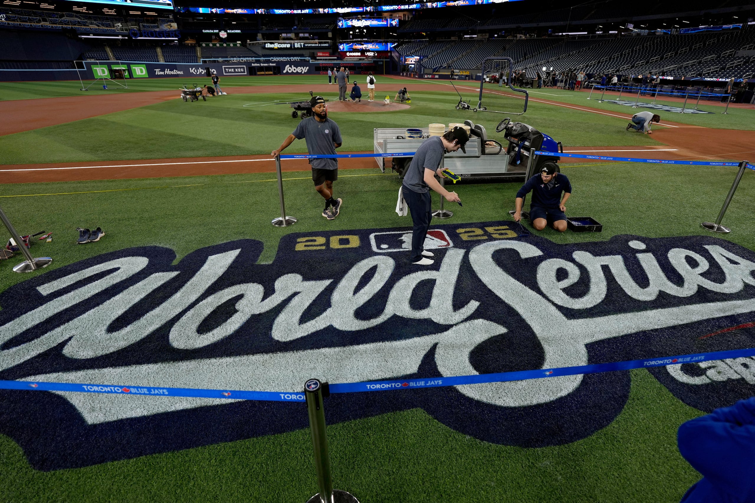 Una cuadrilla alista el logotipo pinado en el terreno del Rogers Centre un día antes de que comience hoy viernes la Serie Mundial en Toronto.