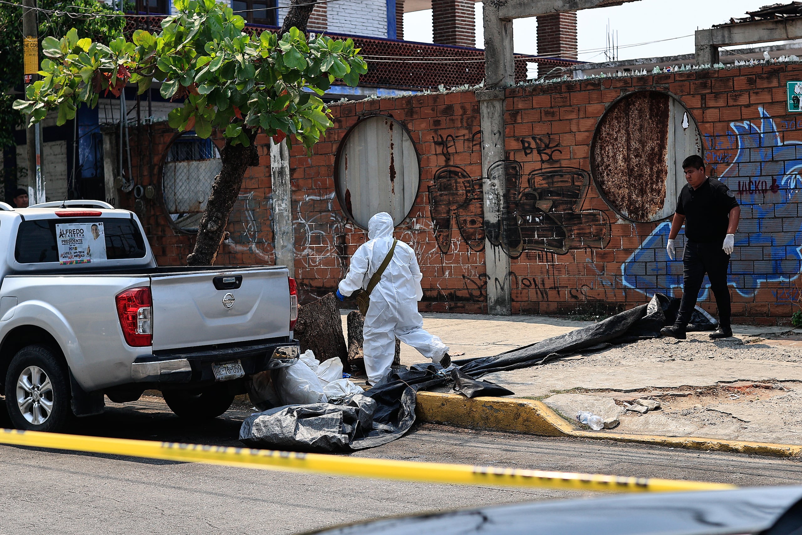 Peritos forenses levantan las bolsas con restos humanos localizadas este jueves, en el balneario de Acapulco.
