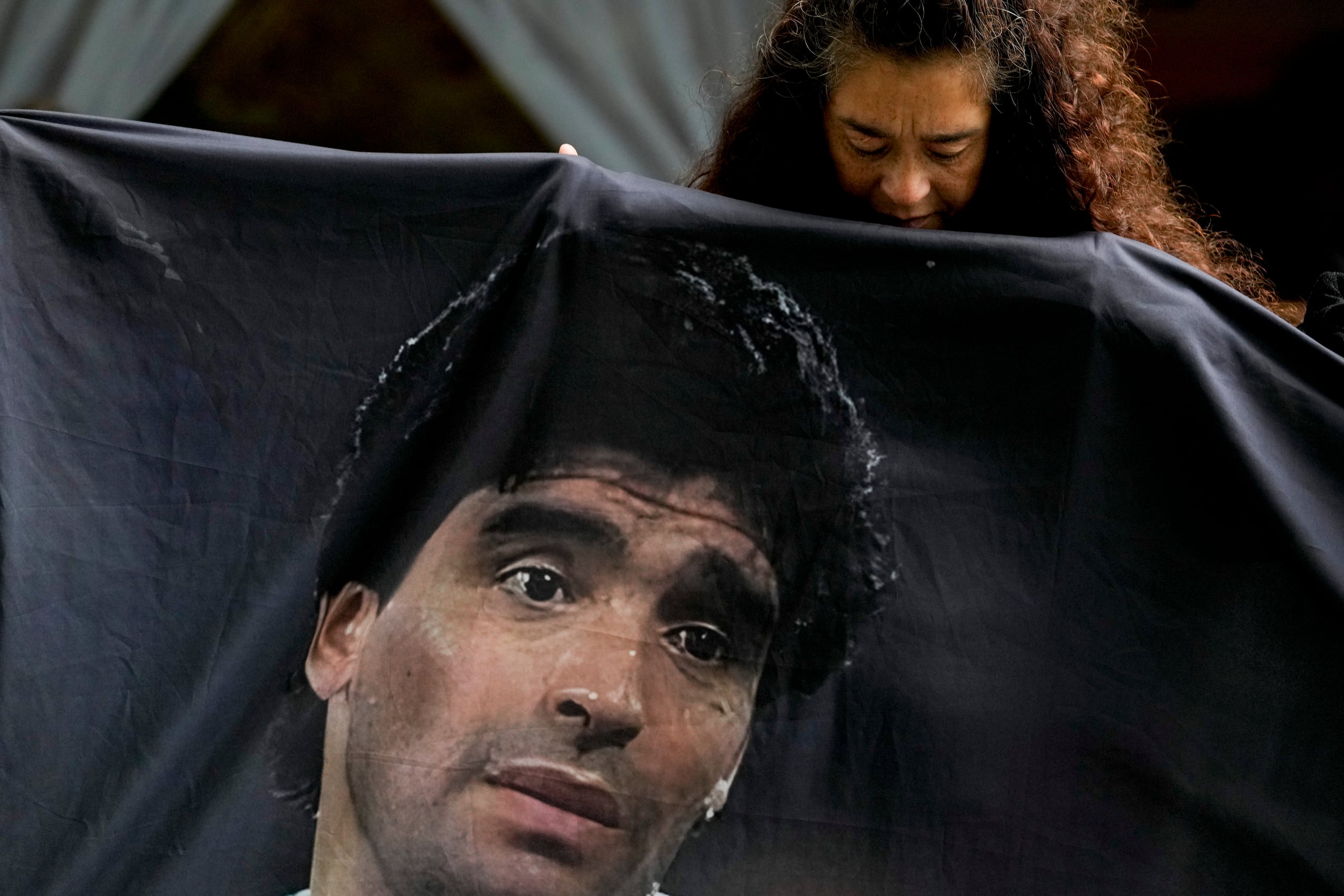 Una fanática de la leyenda del fútbol Diego Maradona sostiene su imagen en las afueras de la corte donde los integrantes del equipo médico que trataron al exfutbolista son juzgados por homicidio en San Isidro, en las afueras de Buenos Aires, Argentina, martes 11 marzo, 2025. (AP Foto/Natacha Pisarenko)