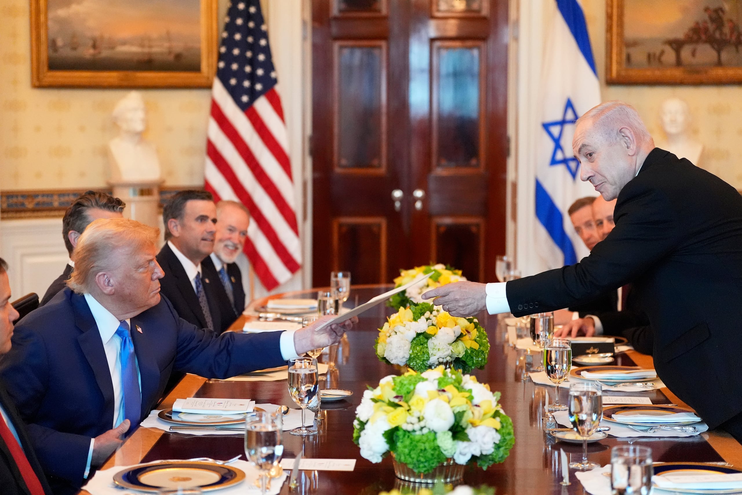 El primer ministro israelí Benjamin Netanyahu, derecha, le entrega al presidente Donald Trump una carpeta durante una reunión en el Salón Azul de la Casa Blanca, el lunes 7 de julio de 2025, en Washington.