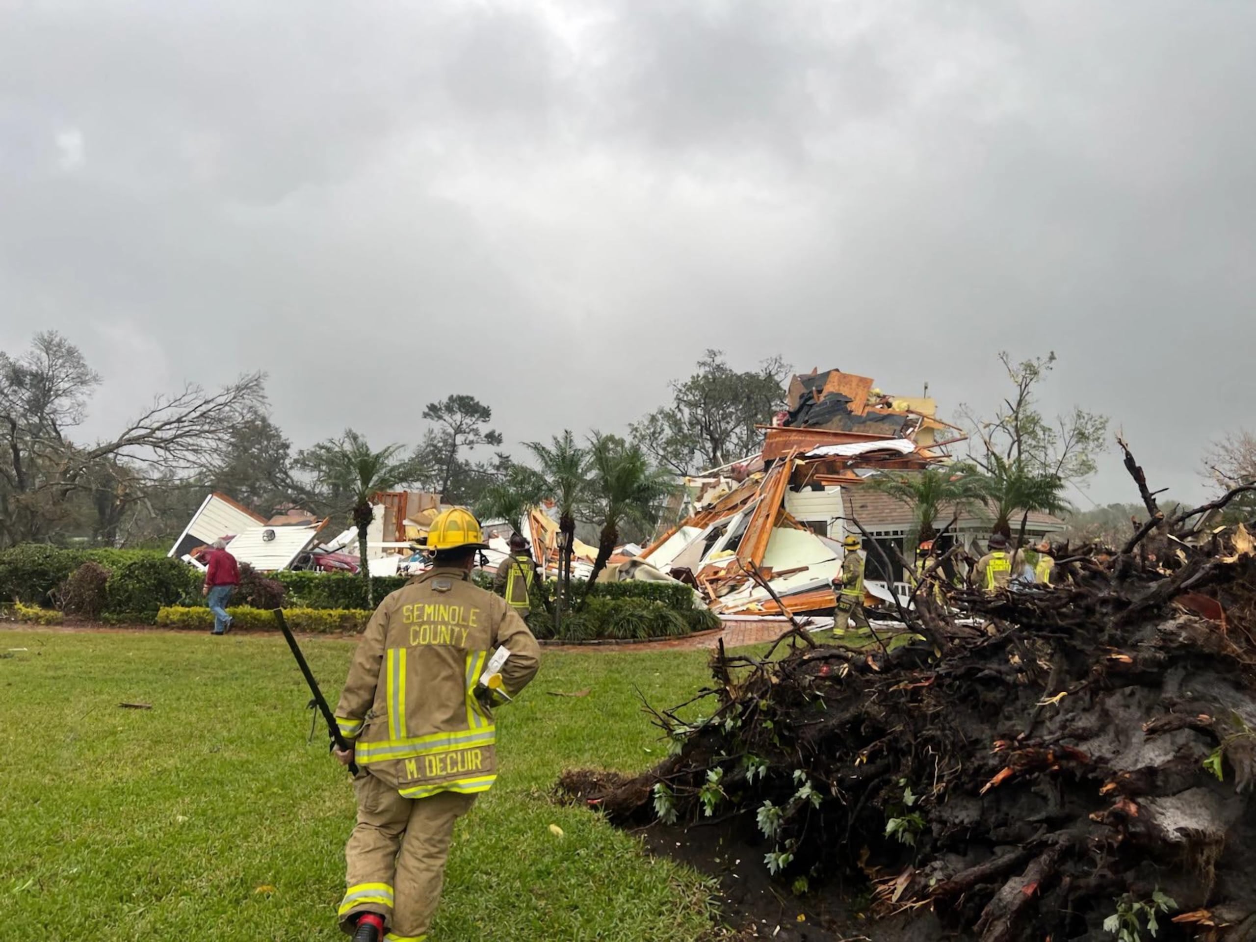 Fotografía cedida por el Departamento de Bomberos del Condado Seminole donde aparece uno de sus agentes mientras observa a una casa destrozada el lunes en Longwood, Florida.