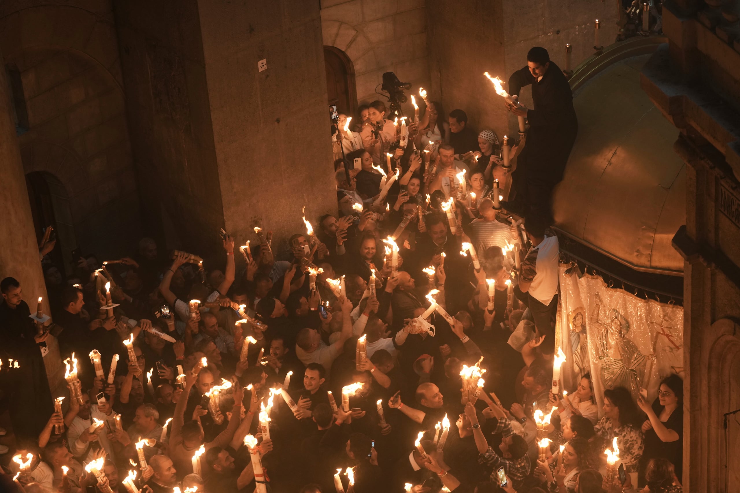 Peregrinos cristianos encienden velas durante la ceremonia del Fuego Sagrado en la Iglesia del Santo Sepulcro, el lugar donde, según la tradición, Jesús fue crucificado y enterrado, en la Ciudad Vieja de Jerusalén, el sábado 19 de abril de 2025. (Foto AP/Mahmoud Illean)