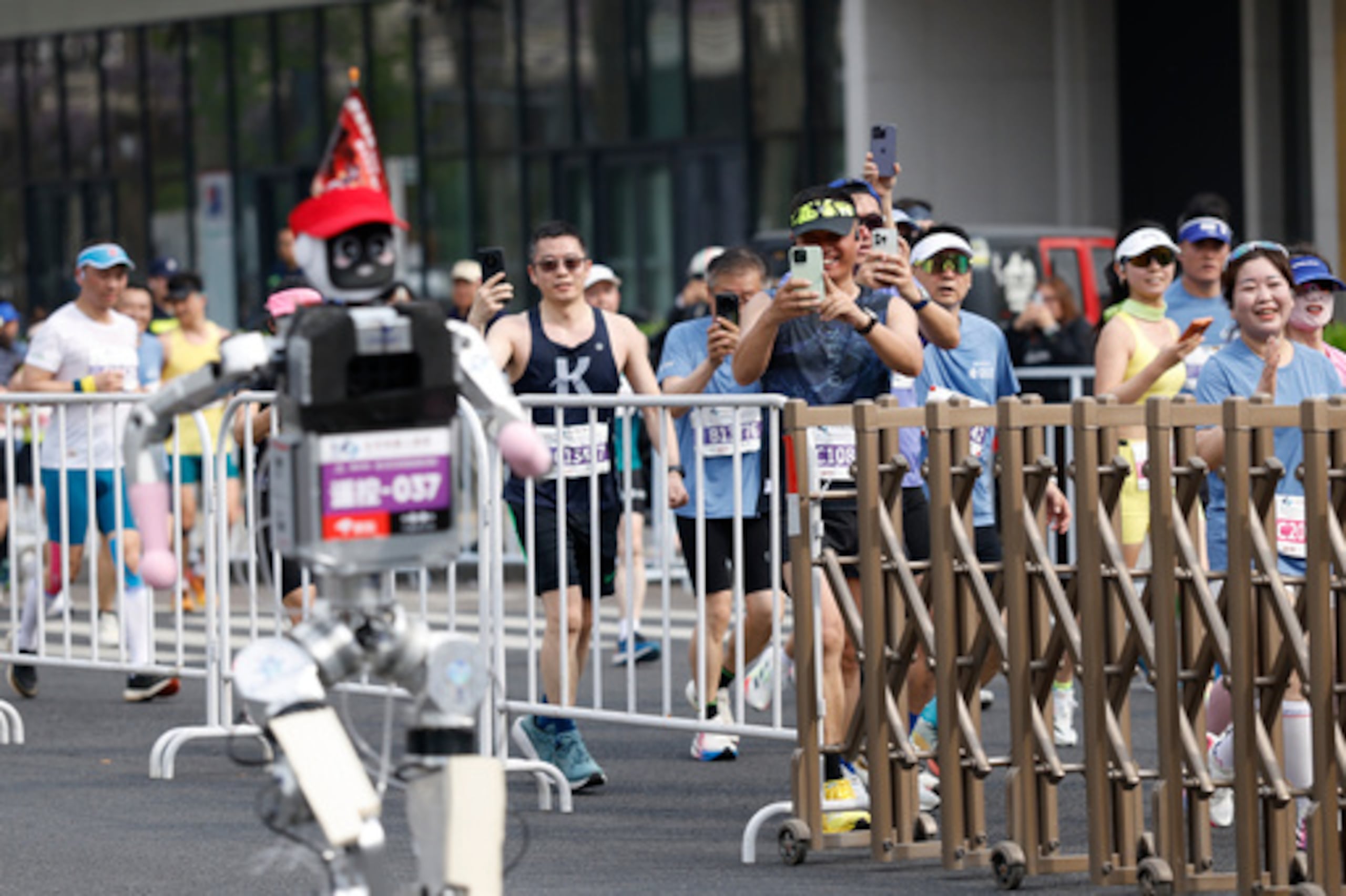 Corredores toman fotos de un robot humanoide en la segunda Media Maratón de Pekín E-Town y Media Maratón de Robots Humanoides en Pekín el domingo 19 de abril de 2026. (Haruna Furuhashi/Pool Photo vía AP)