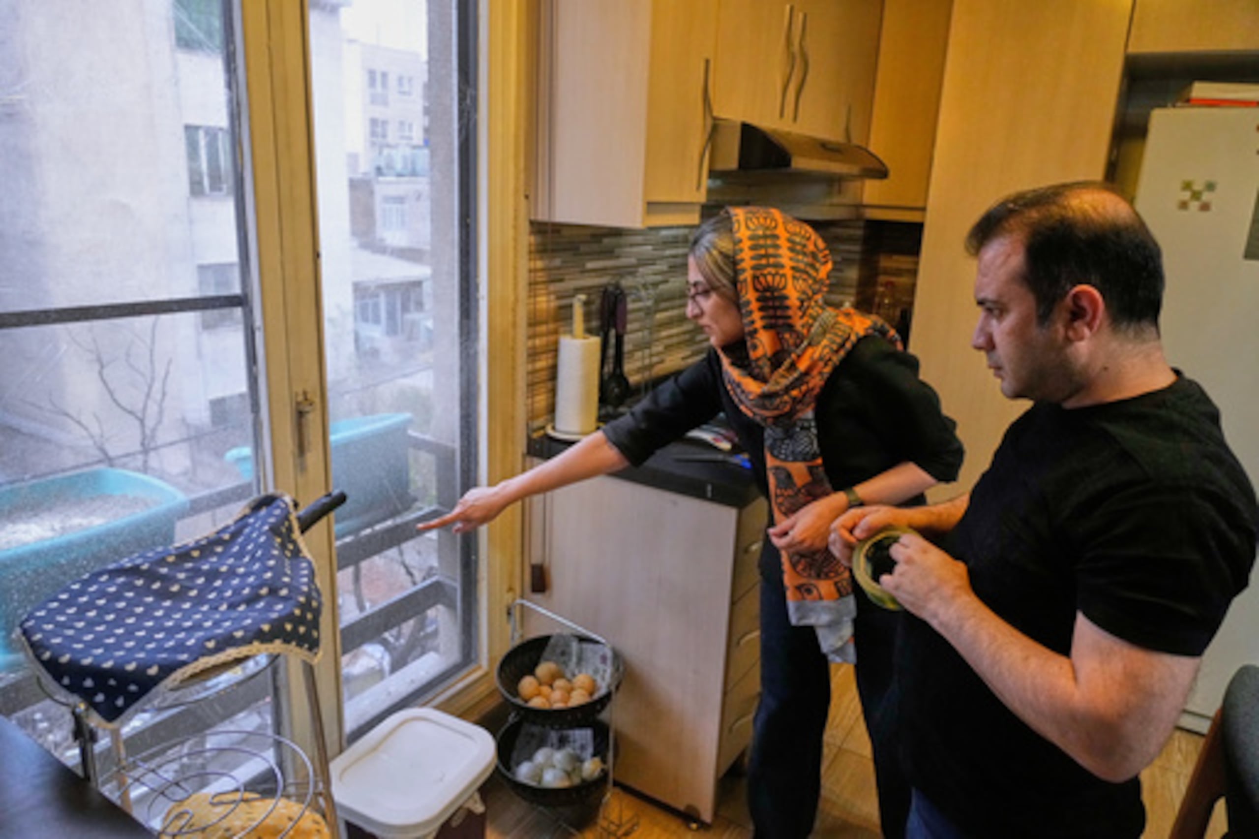 Zahra Arghavan, izquierda, y Mehdi Alishir revisan una de las ventanas de su casa en Teherán, Irán, el domingo 5 de abril de 2026. (AP Photo/Vahid Salemi)
