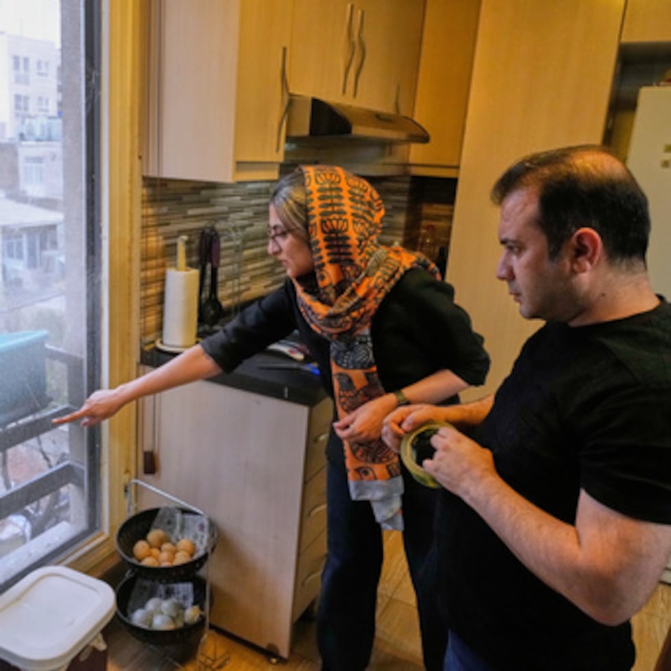 Zahra Arghavan, izquierda, y Mehdi Alishir revisan una de las ventanas de su casa en Teherán, Irán, el domingo 5 de abril de 2026. (AP Photo/Vahid Salemi)