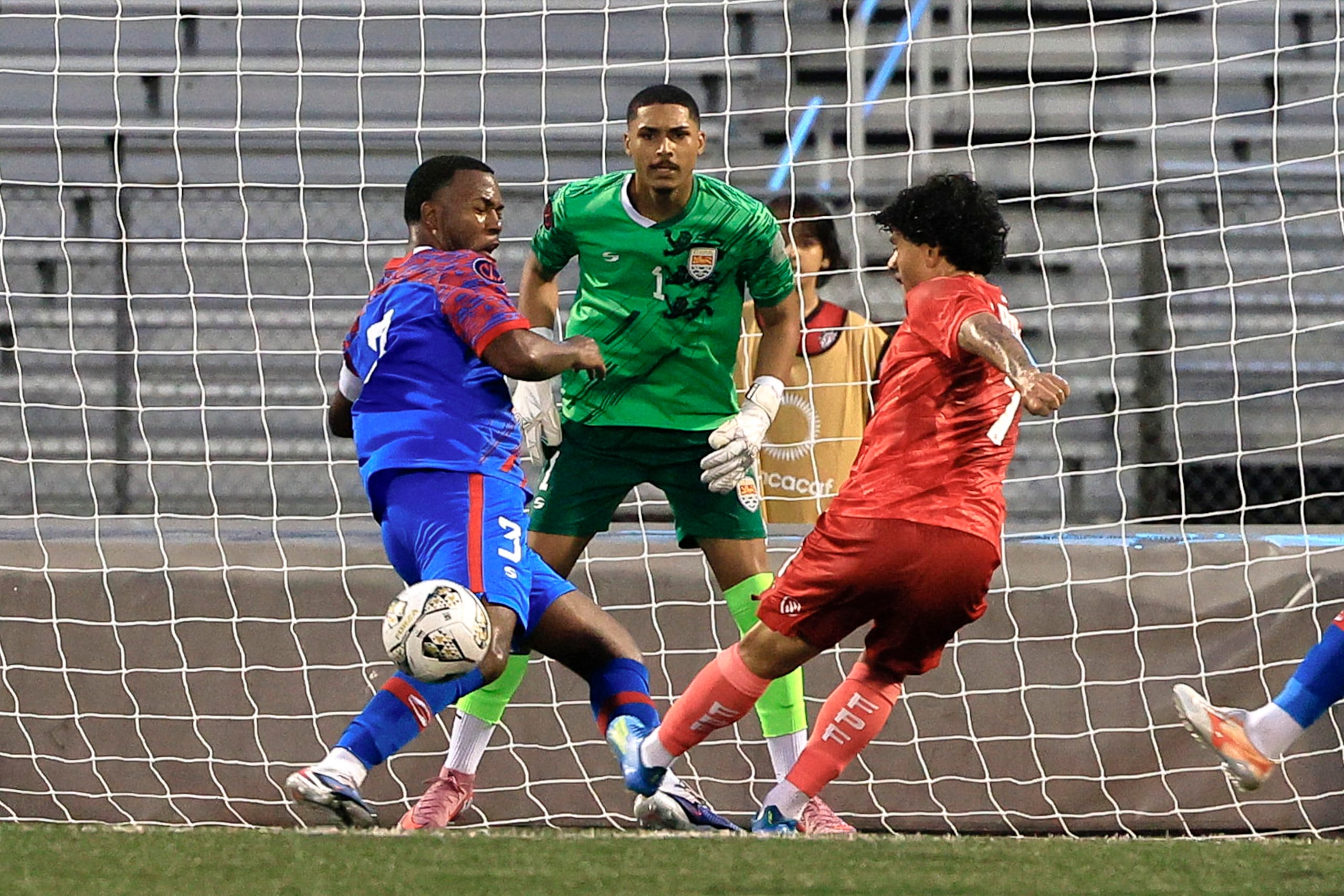 Wilfredo Rivera de Puerto Rico remata frente al portero Deshanwn Whittaker y Andre Row, de Islas Caimán.