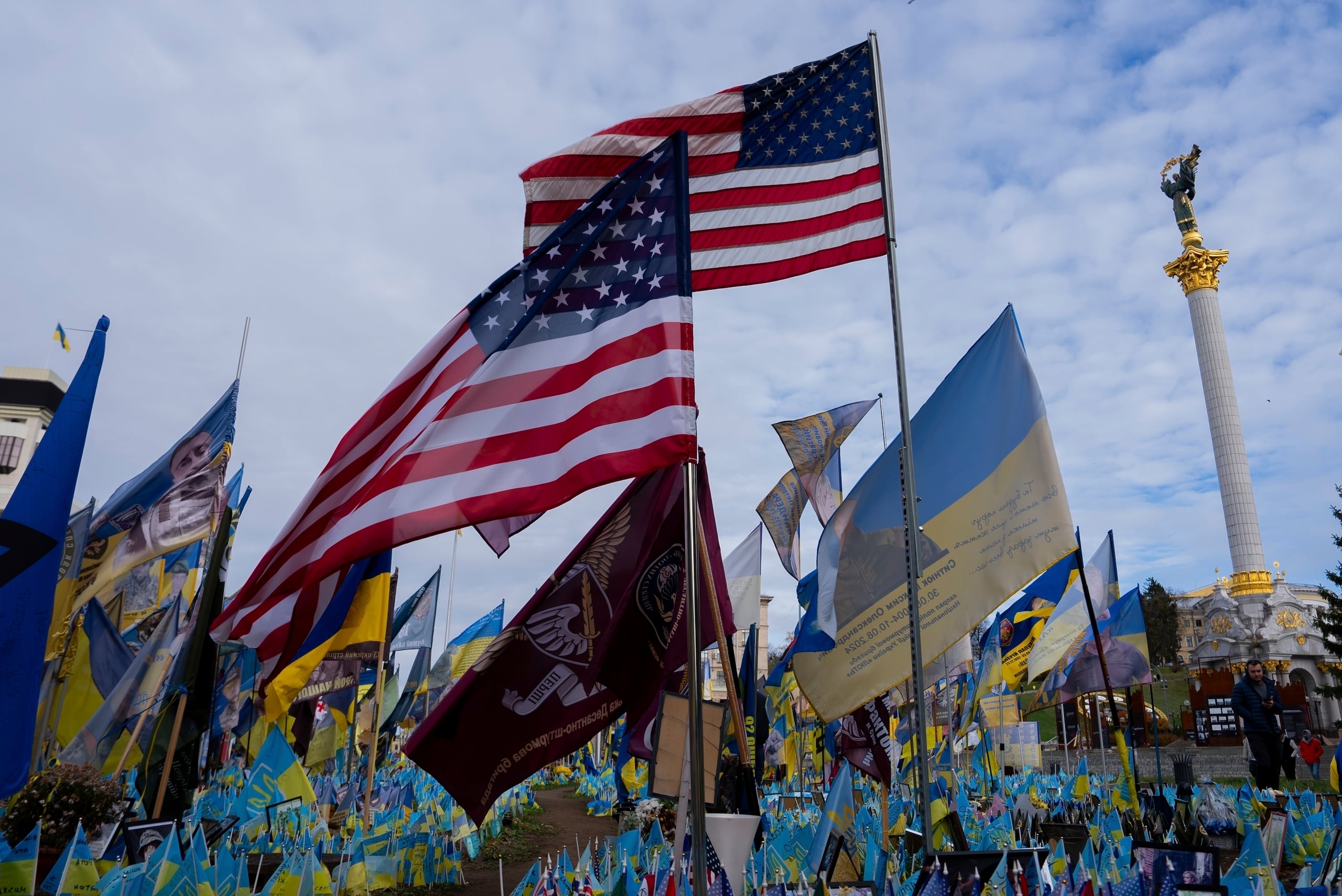 Las banderas de Estados Unidos y Ucrania en honor de los soldados caídos ondean frente a una estatua en la plaza central, en Kiev, Ucrania.
