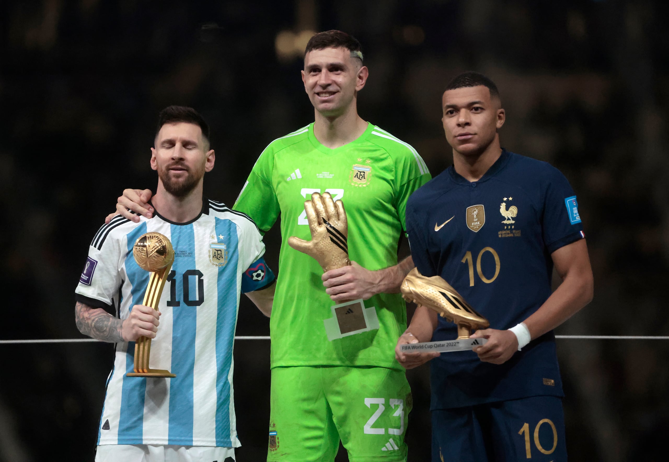 Los argentinos Lionel Messi (izquierda) y Emiliano Martínez (centro) y el francés Kylian Mbappé muestran sus premios.