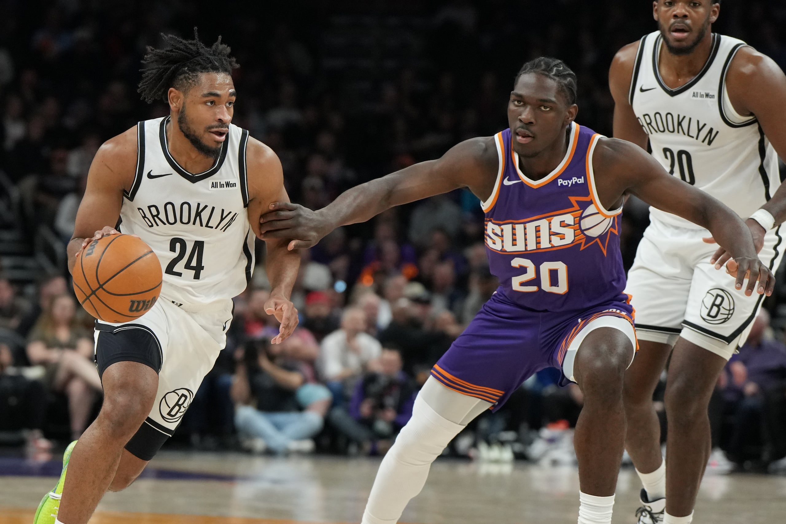 Cam Thomas (24), de los Nets de Brooklyn, avanza ante Rasheer Fleming (20), de los Suns de Phoenix, durante la primera mitad de un partido de la NBA, el martes 27 de enero de 2026, en Phoenix. (AP Photo/Rick Scuteri)