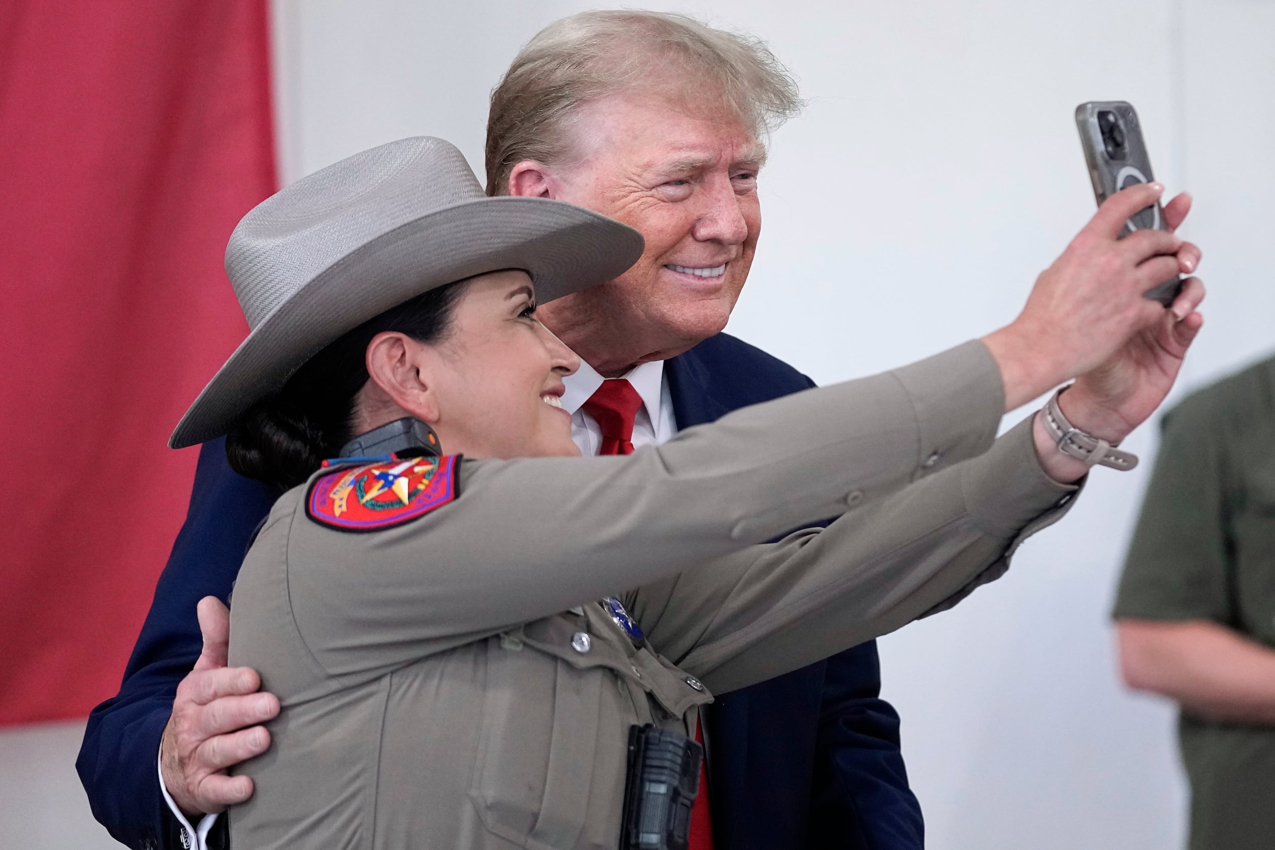El candidato presidencial republicano y expresidente Donald Trump posa para una fotografía con un policía estatal de Texas mientras ayuda a servir comida a los soldados, policías y otras personas de la Guardia Nacional de Texas, el domingo 19 de noviembre de 2023, en Edimburgo, Texas. (Foto AP/Eric Gay)