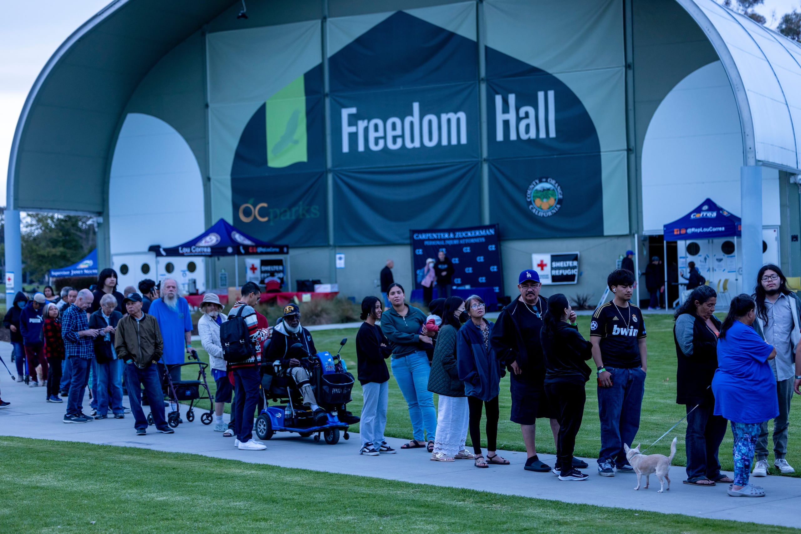 Varias personas hacen fila para cenar frente al Freedom Hall, donde se ha habilitado un refugio para evacuados en el parque regional Mile Square, el sábado 23 de mayo de 2026, en Fountain Valley, California. (AP Foto/Jill Connelly)