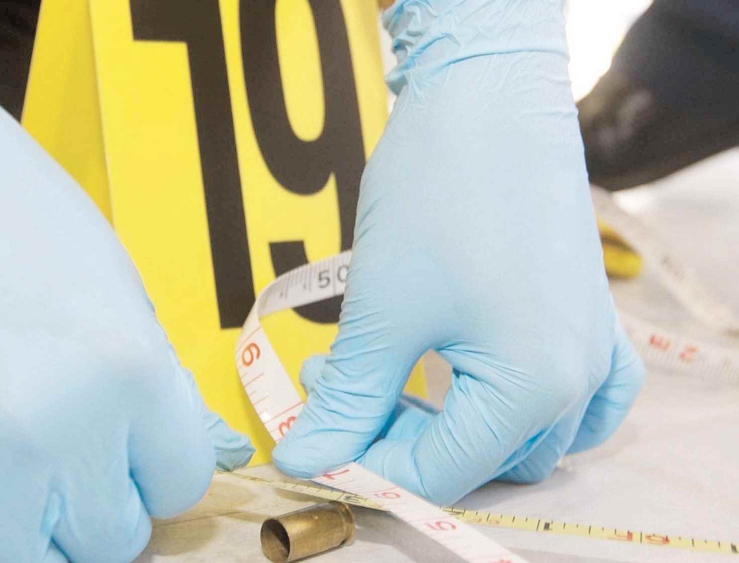 Un agente de la Policía analiza un casquillo de bala en una escena de un asesinato. (GFR Media)