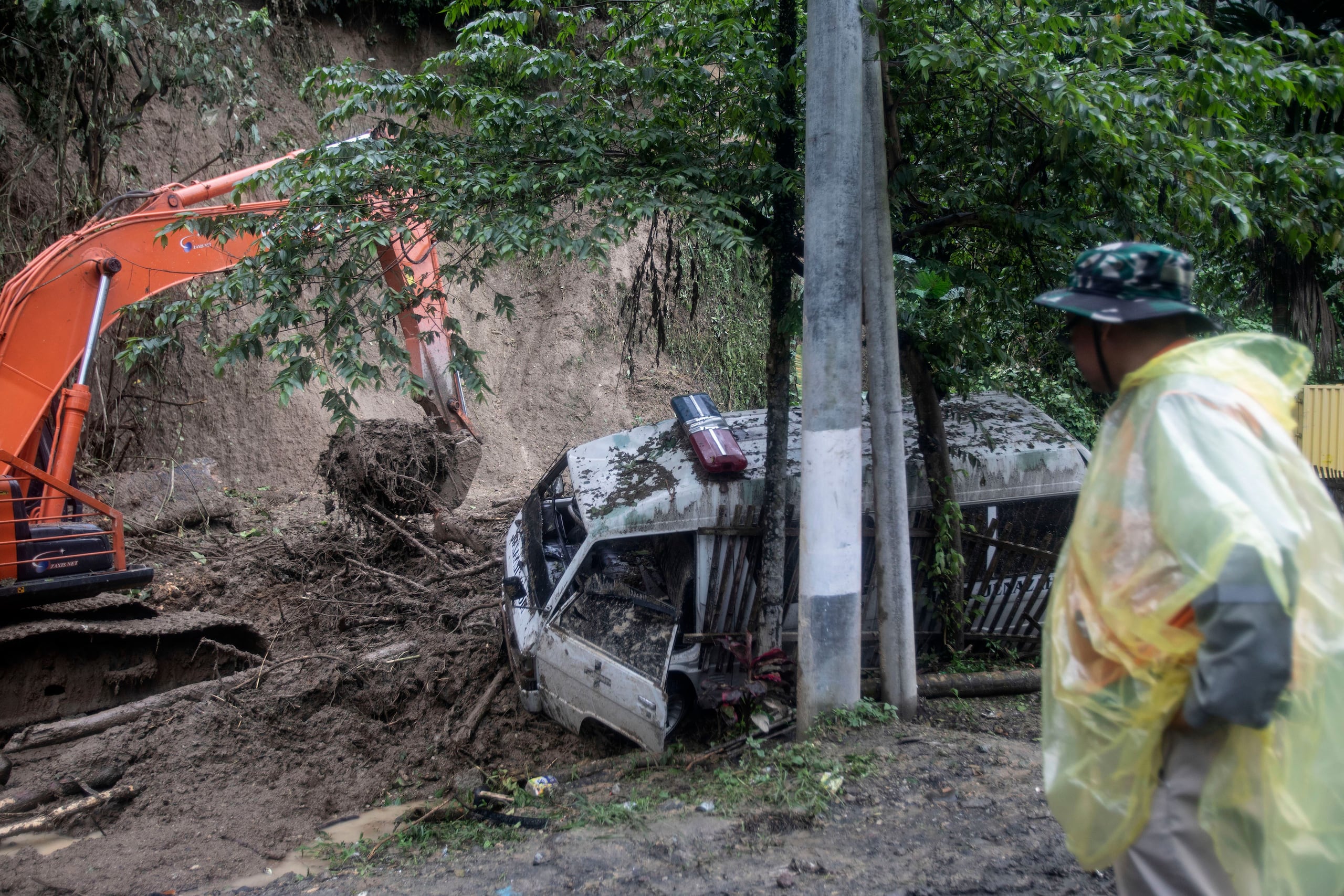 Un rescatista observa cómo una máquina pesada limpia el lodo después de que un deslave arrasara una carretera matando a varias personas en Sibolangit, Sumatra del Norte, Indonesia.
