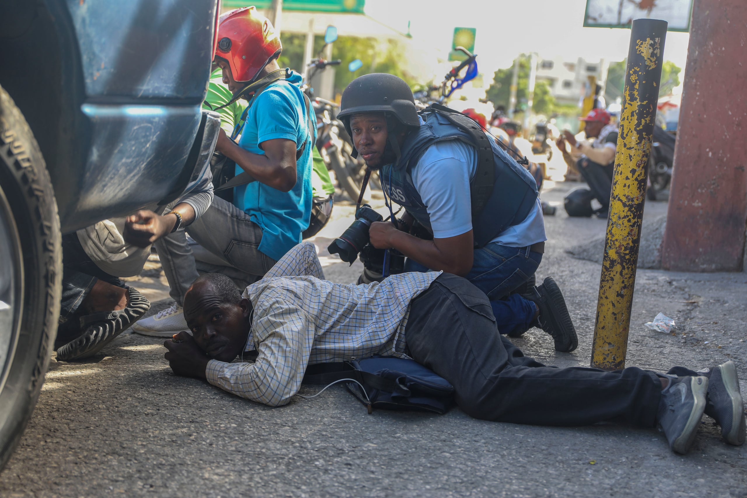 Periodistas se cubren del cruce de disparos entre pandillas y la policía en Puerto Príncipe, Haití.