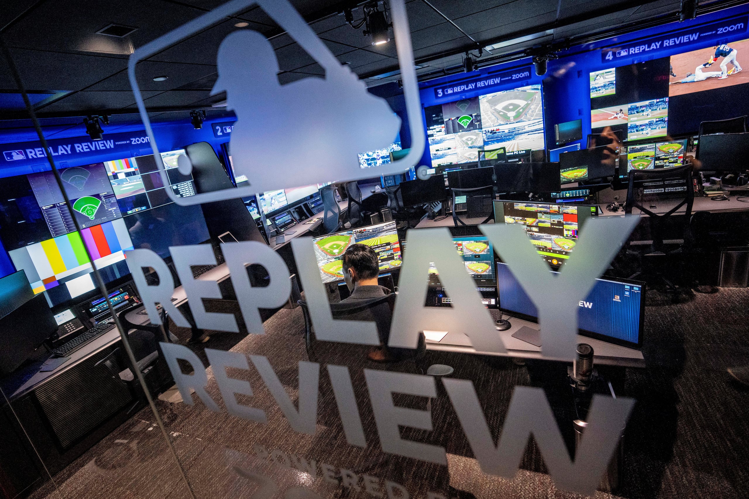 Un empleado trabaja en un puesto de apoyo dentro de la sala de revisión de repeticiones en la sede de las Grandes Ligas de Béisbol (MLB) en Nueva York, el martes 28 de marzo de 2023.