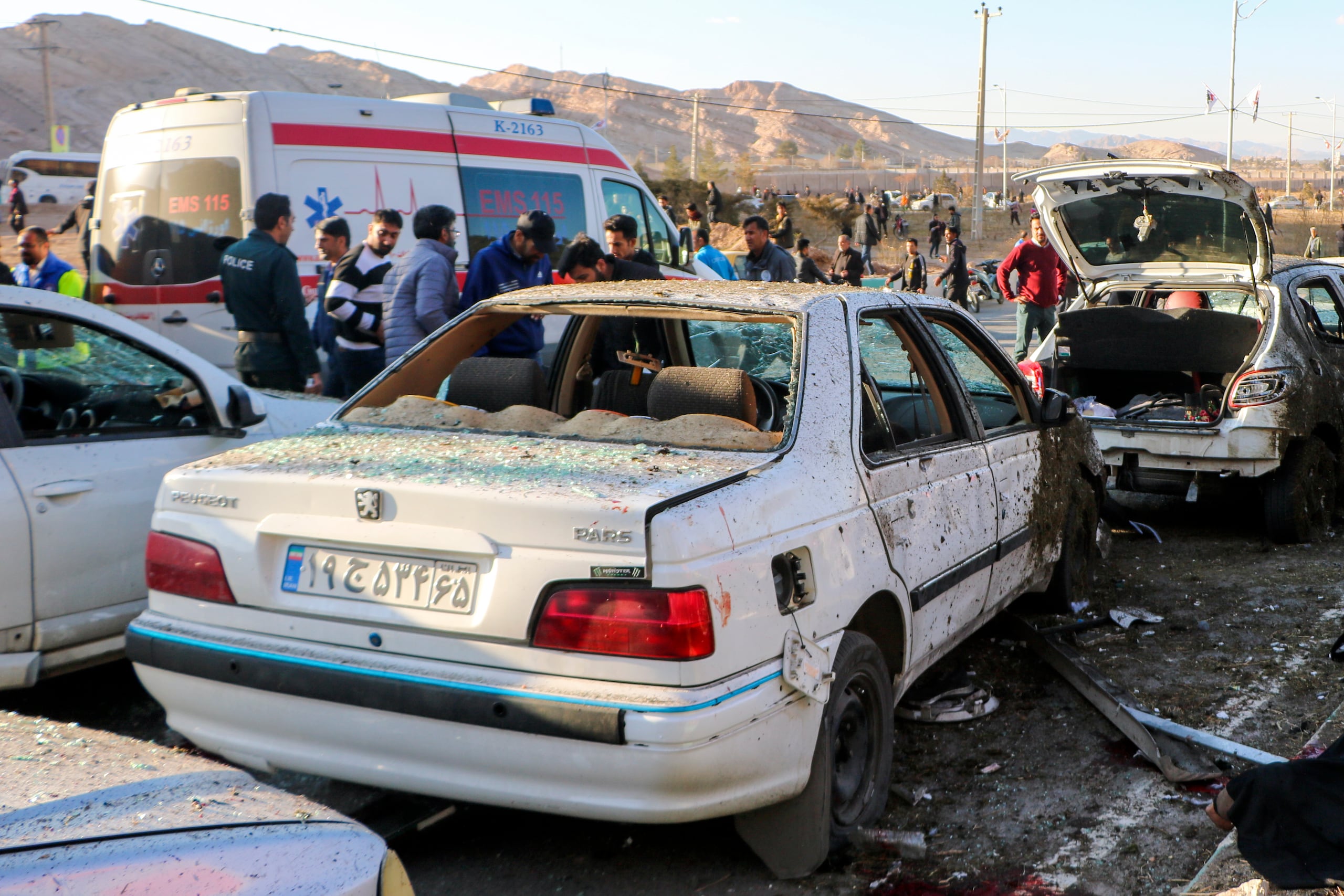Varias personas junto a automóviles destrozados luego de las explosiones en Kermán, Irán, el 3 de enero de 2024.