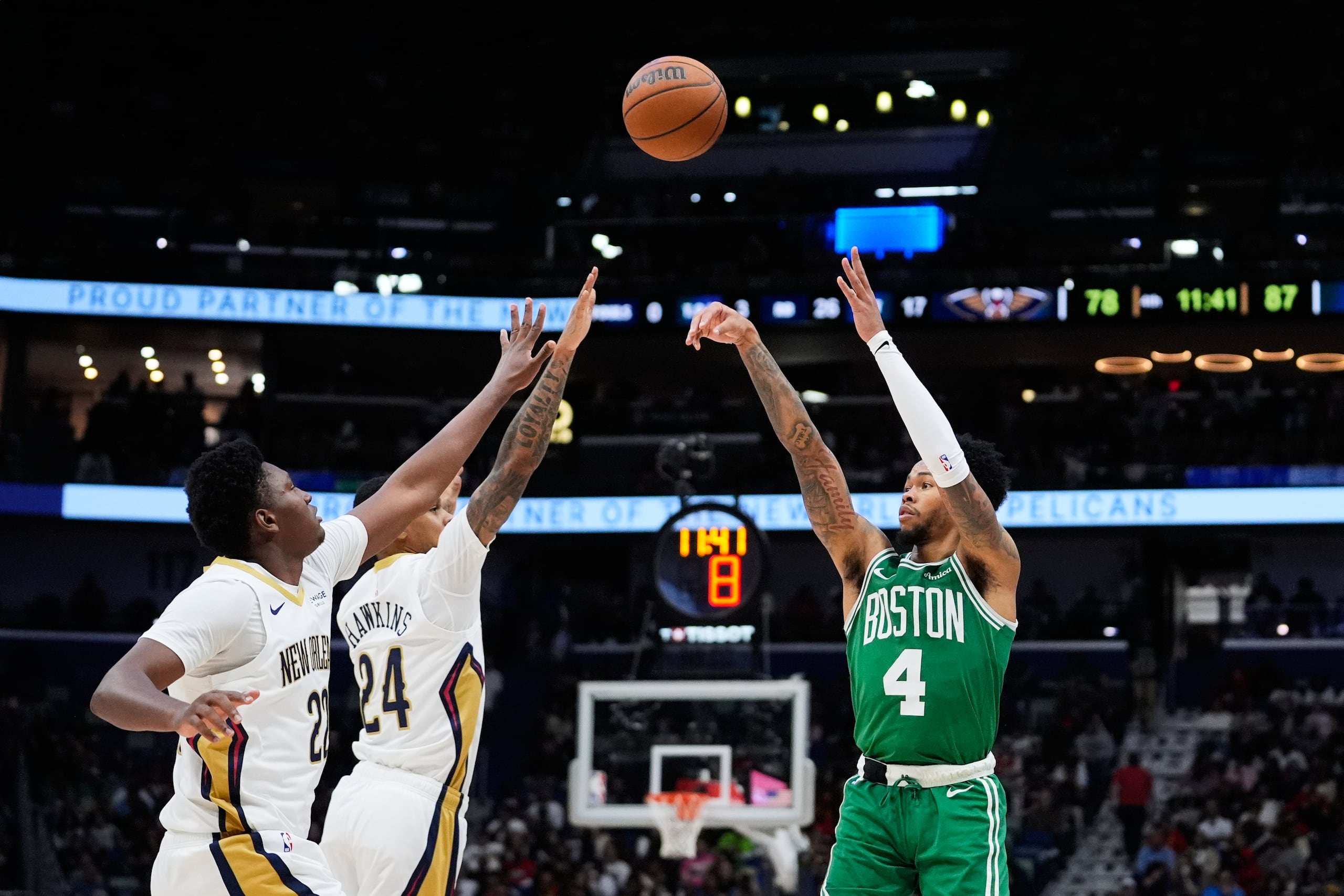 El base de los Celtics de Boston Anfernee Simons lanza el balón frente al base Jordan Hawkins y el pívot Derik Queen de los Pelicans de Nueva Orleans el lunes 27 de octubre del 2025. (AP Foto/Gerald Herbert)