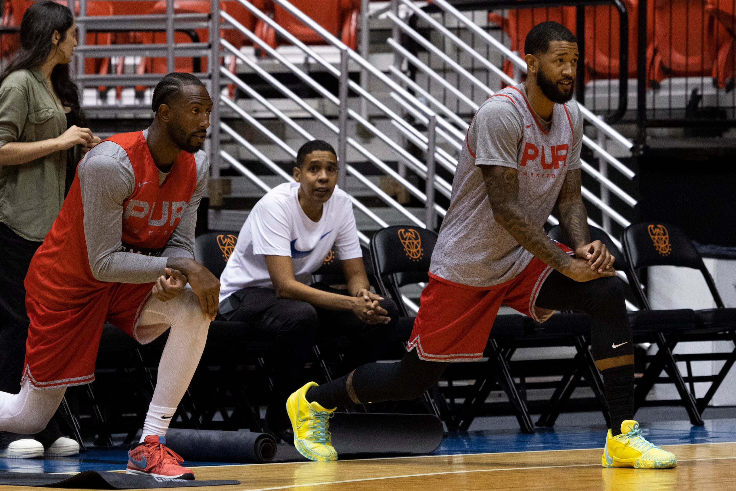 Davon Reed y Chris Ortiz, del Equipo Nacional, hacen ejercicios de estiramientos antes de salir a practicar.