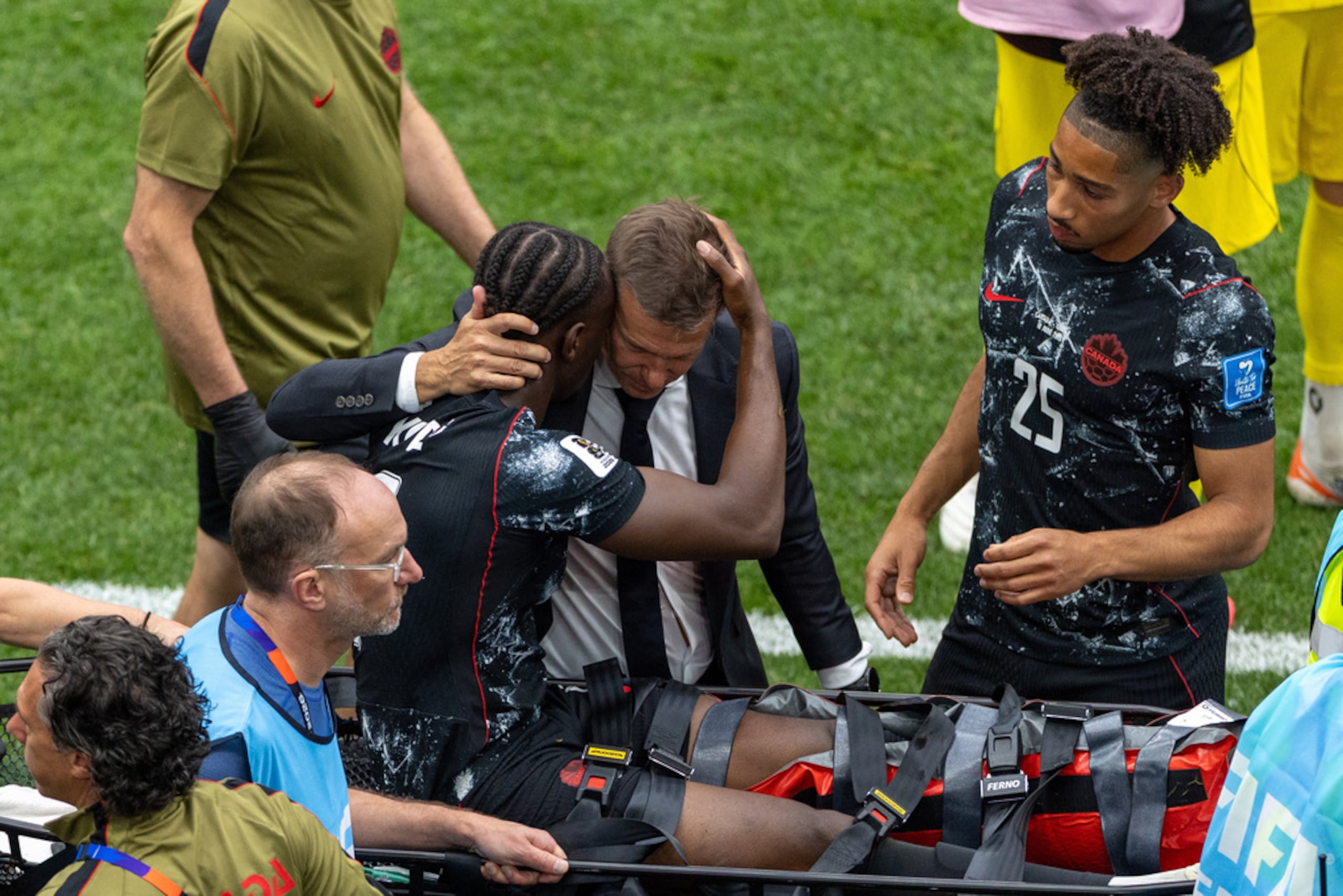 El técnico de Canadá, Jesse Marsch, abraza a Ismaël Koné mientras sale retirado en camilla.