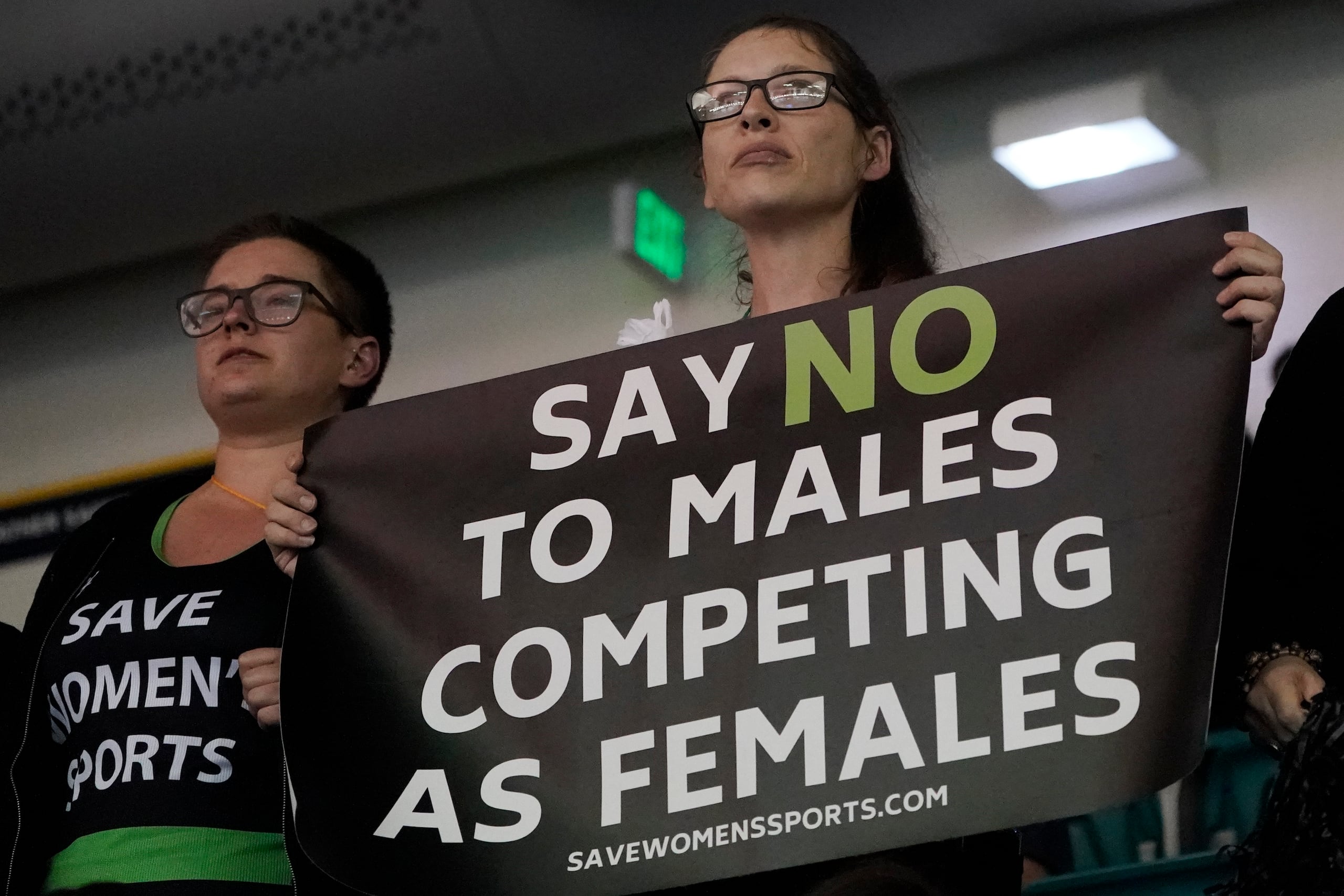 Protester hold signs as University of Pennsylvania transgender athlete Lia Thomas competes in the 200 freestyle finals at the NCAA Swimming and Diving Championships Friday, March 18, 2022, at Georgia Tech in Atlanta. Thomas finished tied for fifth place. (AP Photo/John Bazemore)