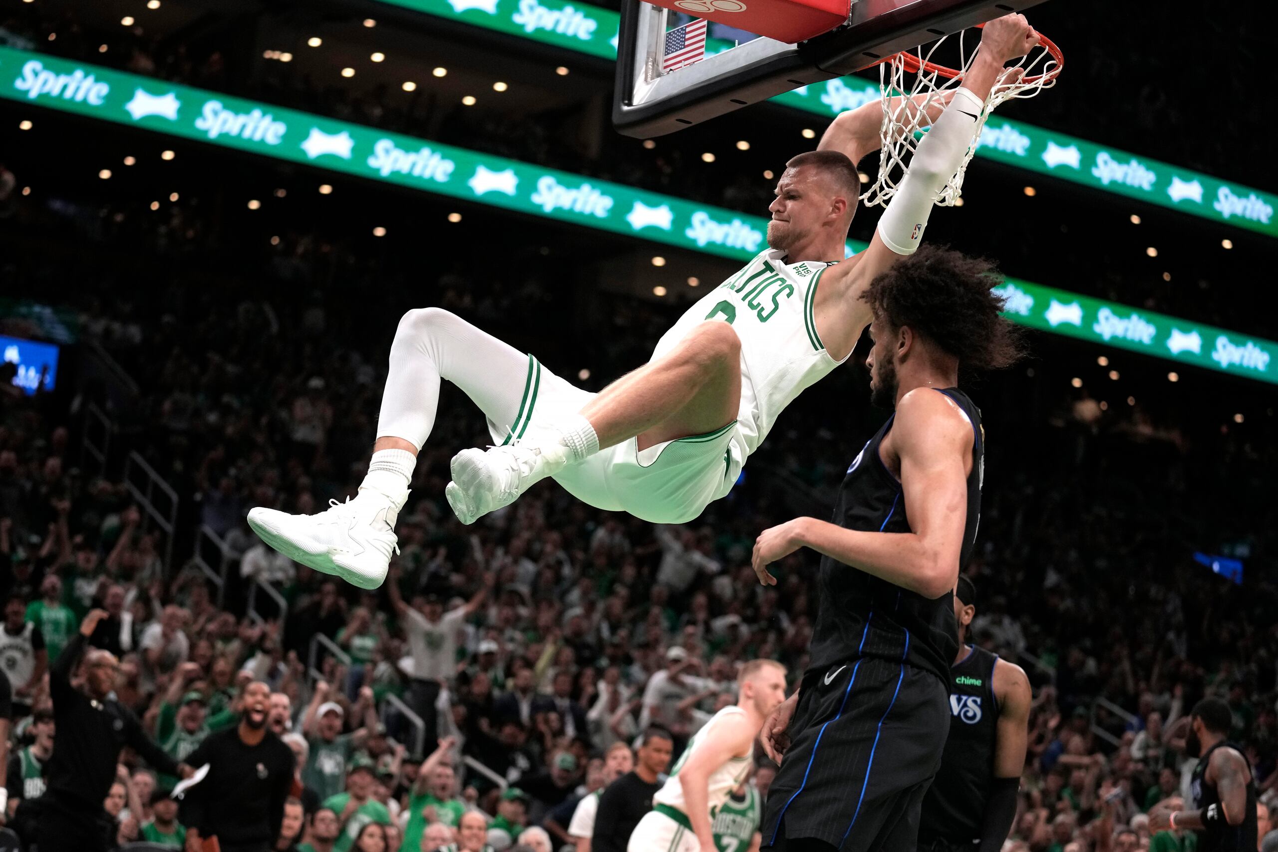 Kristaps Porzingis, de los Celtics de Boston, donquea frente a Dereck Lively II, de los Mavericks de Dallas.