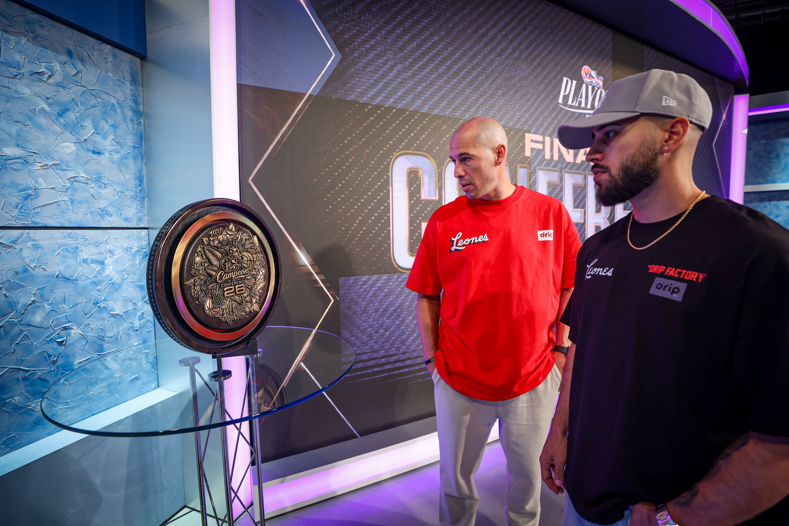 Carlos Rivera y Tjader Fernández, dirigente y jugador de los Leones de Ponce, respectivamente, observan el nuevo trofeo que se entregará a los campeones de conferencia del BSN.