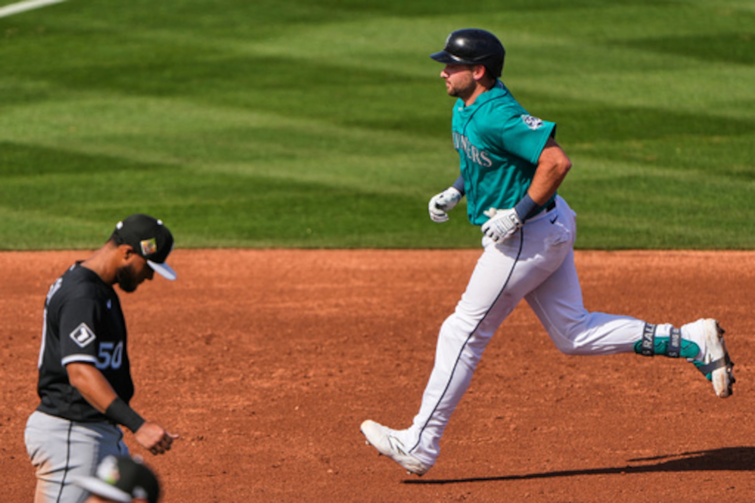 Cal Raleigh, de los Marineros de Seattle, corre por las bases ante el tercera base de los Medias Blancas de Chicago, Lenyn Sosa, tras batear un jonrón de dos carreras durante la tercera entrada de un partido de béisbol de entrenamiento de primavera el martes 24 de febrero de 2026, en Peoria, Arizona (AP Photo/Charlie Riedel).