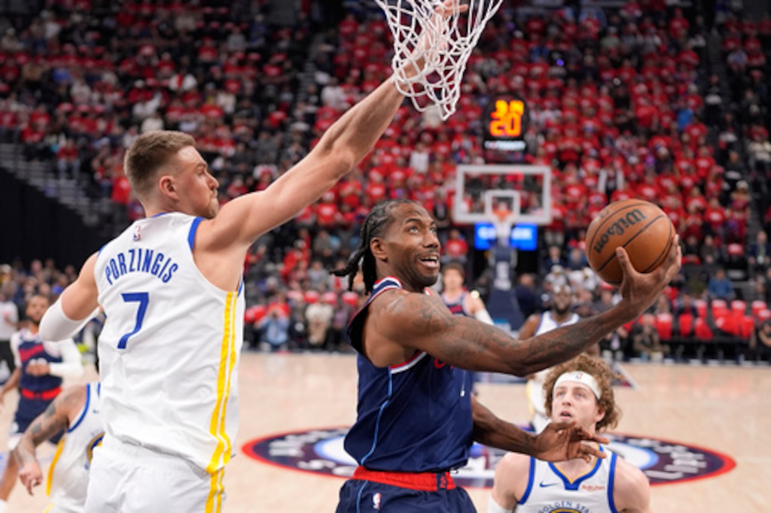 Kawhi Leonard (en el centro), lanza a canasta mientras el pívot de los Golden State Warriors, Kristaps Porzingis, le defiende durante la primera parte de un partido del torneo de play-in de la NBA de la recién concluida campaña de la NBA.