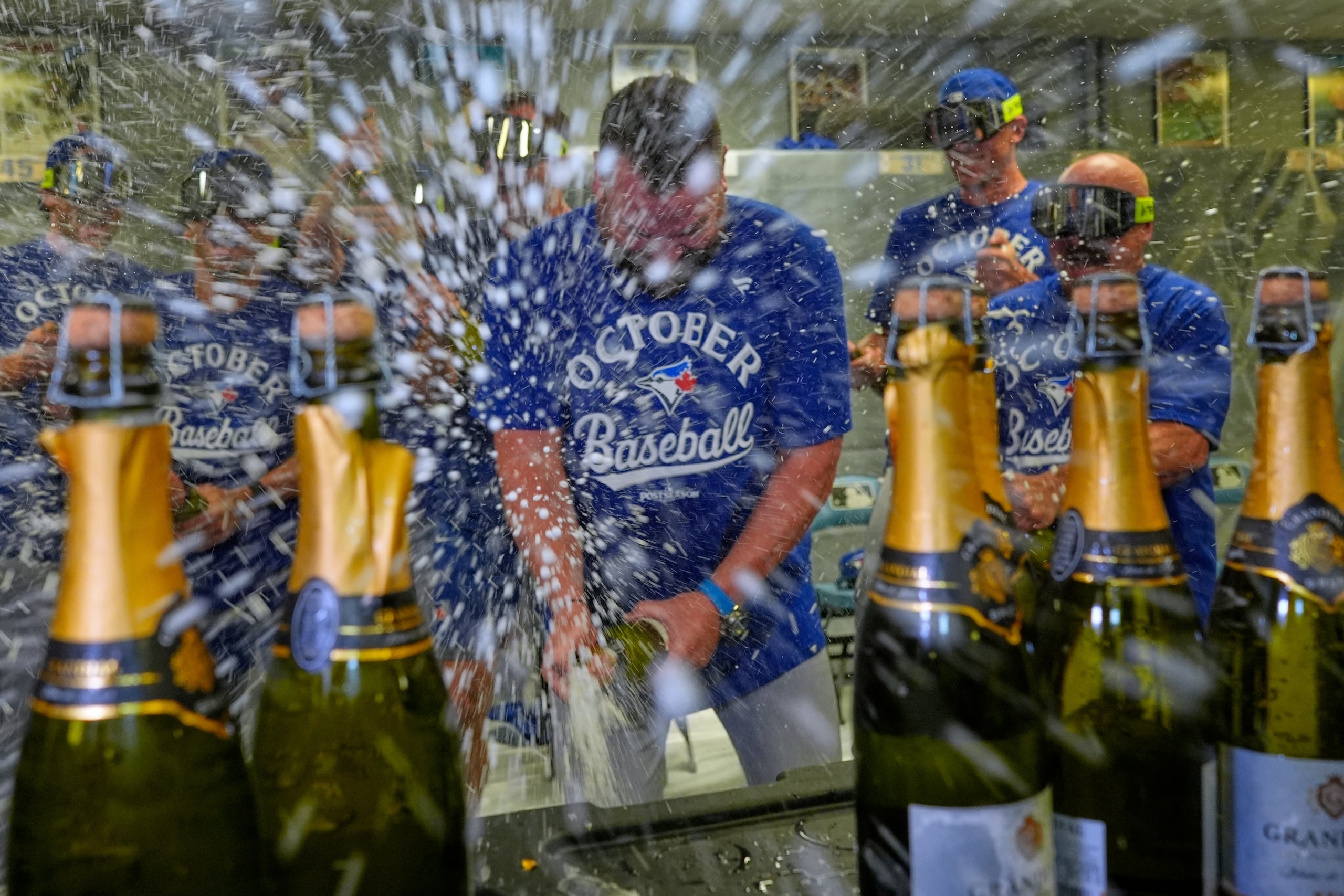 El mánager de los Toronto Blue Jays, John Schneider, en el centro, celebra con los jugadores en el clubhouse.