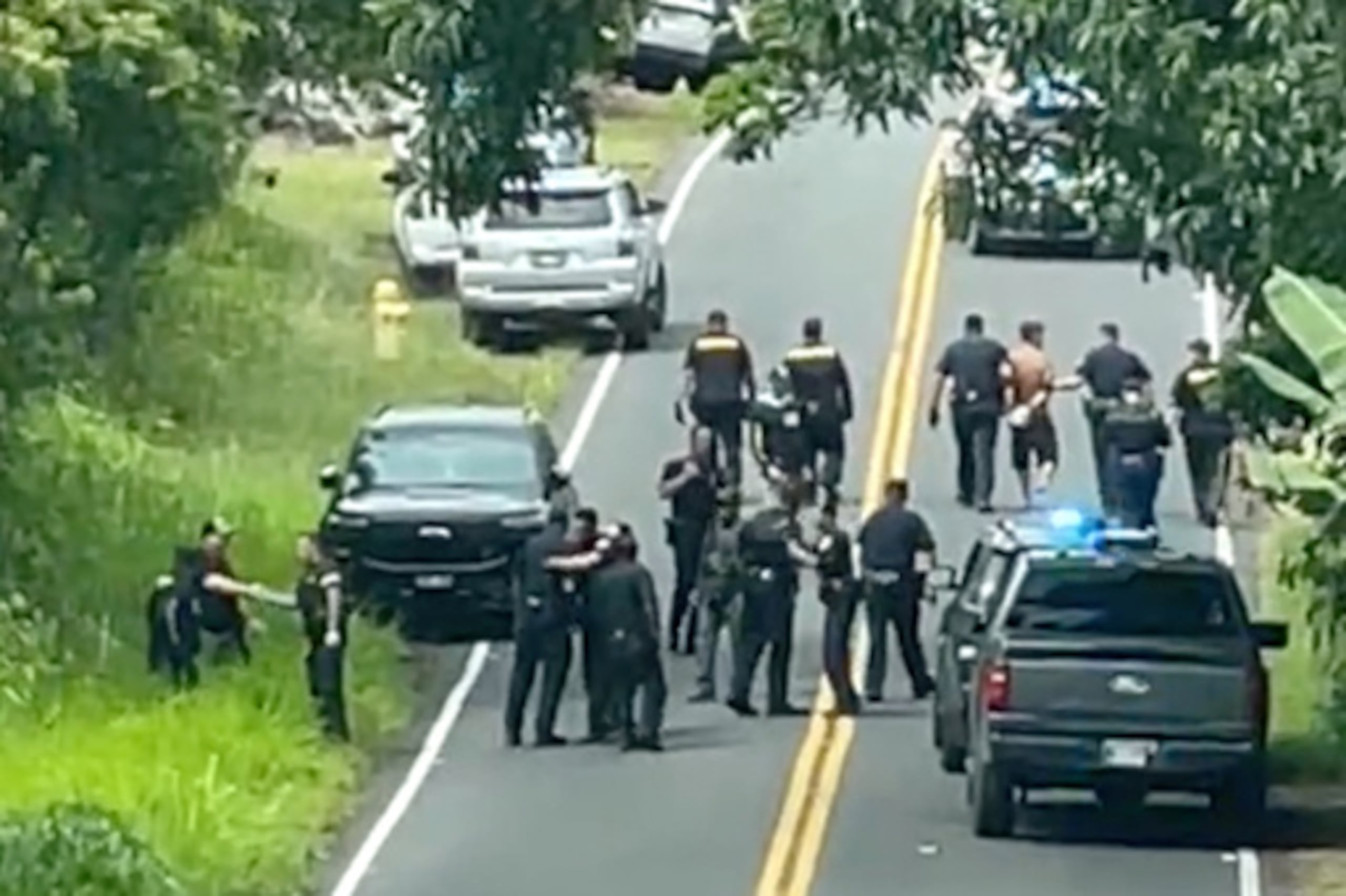 La policía detiene a un hombre acusado de múltiples asesinatos, a la derecha, el jueves 28 de mayo de 2026, en Kaimu, Hawái. (Deborah Davis vía AP)
