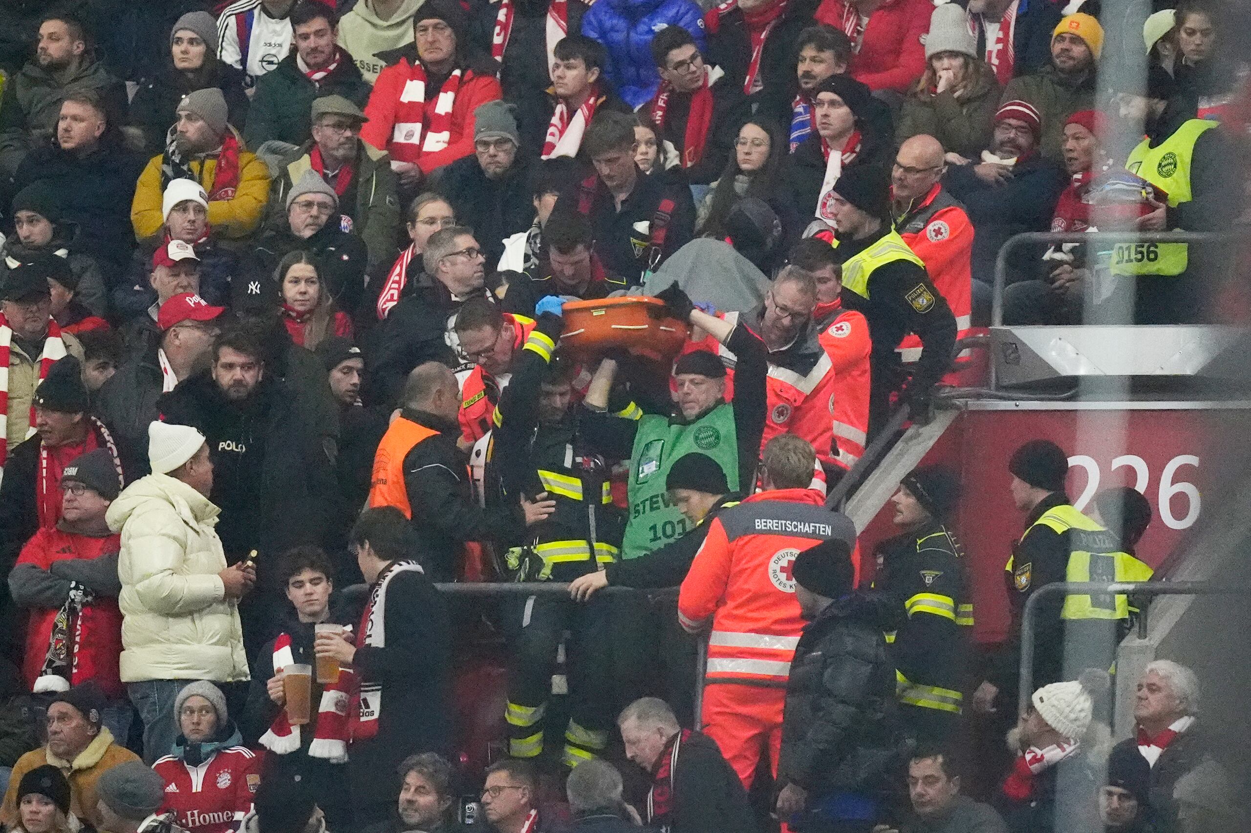 Agentes policiales y paramédicos cargan una camilla en el graderío durante una emergencia médica en el partido de la Liga de Campeones, entre el local Bayern Múnich y el Benfica, el miércoles 6 de noviembre de 2024 (AP Foto/Matthias Schrader)