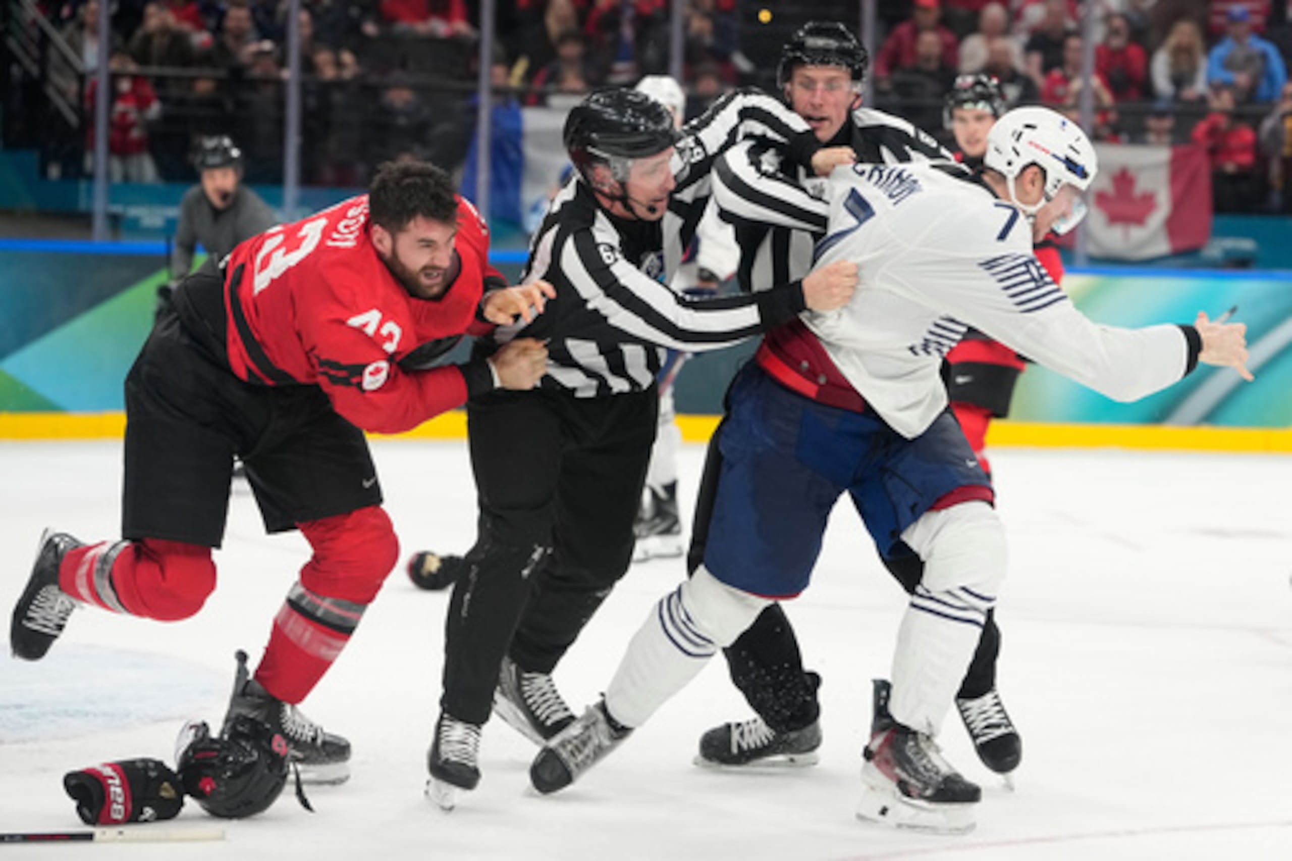 Pierre Crinon (7) de Francia y Tom Wilson (43) de Canadá luchan en el tercer periodo durante un partido de la ronda preliminar de hockey sobre hielo masculino entre Canadá y Francia en los Juegos Olímpicos de Invierno de 2026, en Milán, Italia, el domingo 15 de febrero de 2026. (AP Photo/Hassan Ammar)