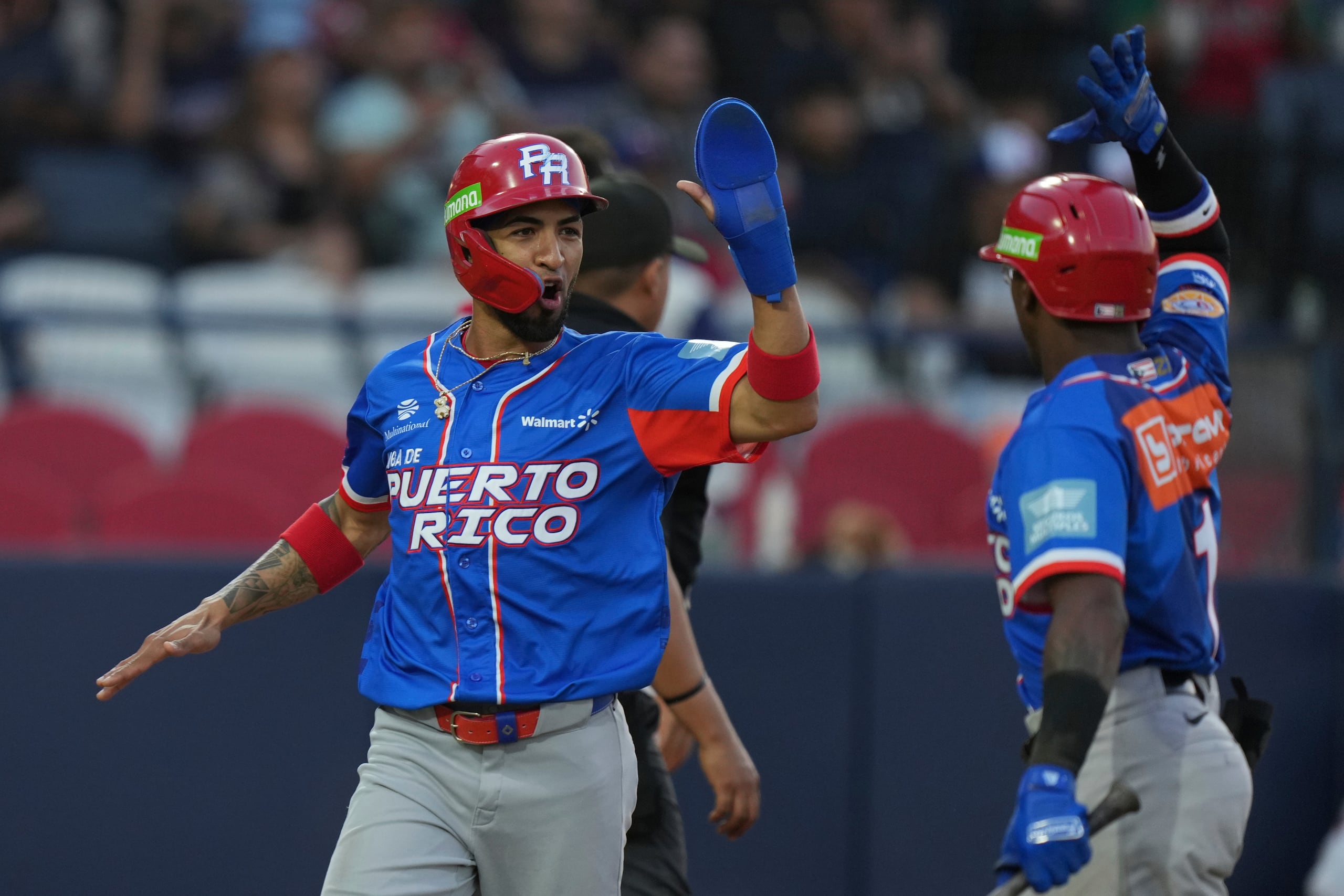 Eddie Rosario, de Puerto Rico, a la izquierda, celebra tras anotar contra República Dominicana durante un partido de la Serie del Caribe en el Estadio Nido de los Águilas en Mexicali, México.