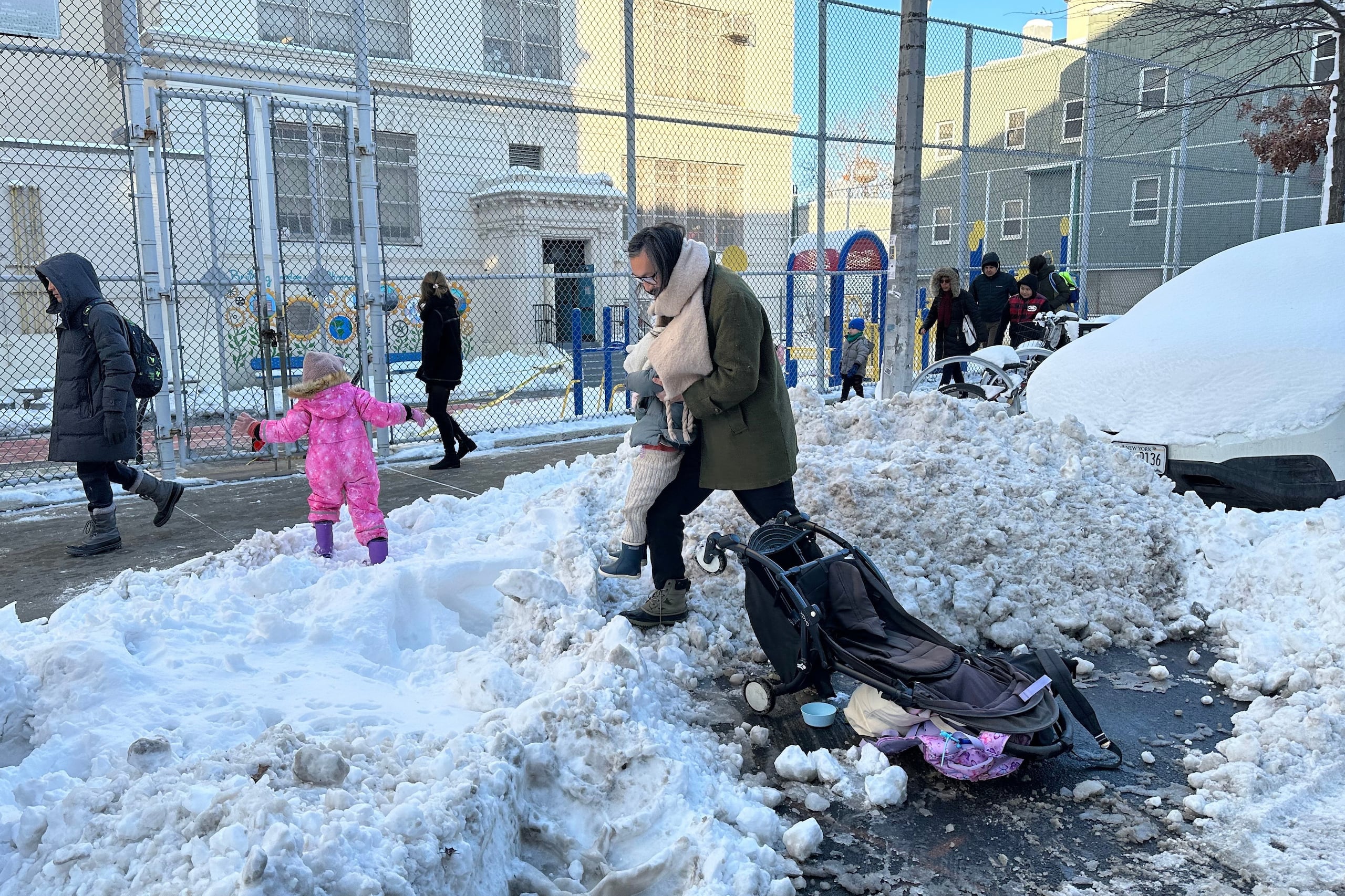 Estudiantes y padres del barrio Greenpoint de Brooklyn pasan entre la nieve camino al colegio mientras las clases se reanudan en Nueva York tras la tormenta invernal, el martes 24 de febrero de 2026. (Foto AP/Jake Offenhartz)