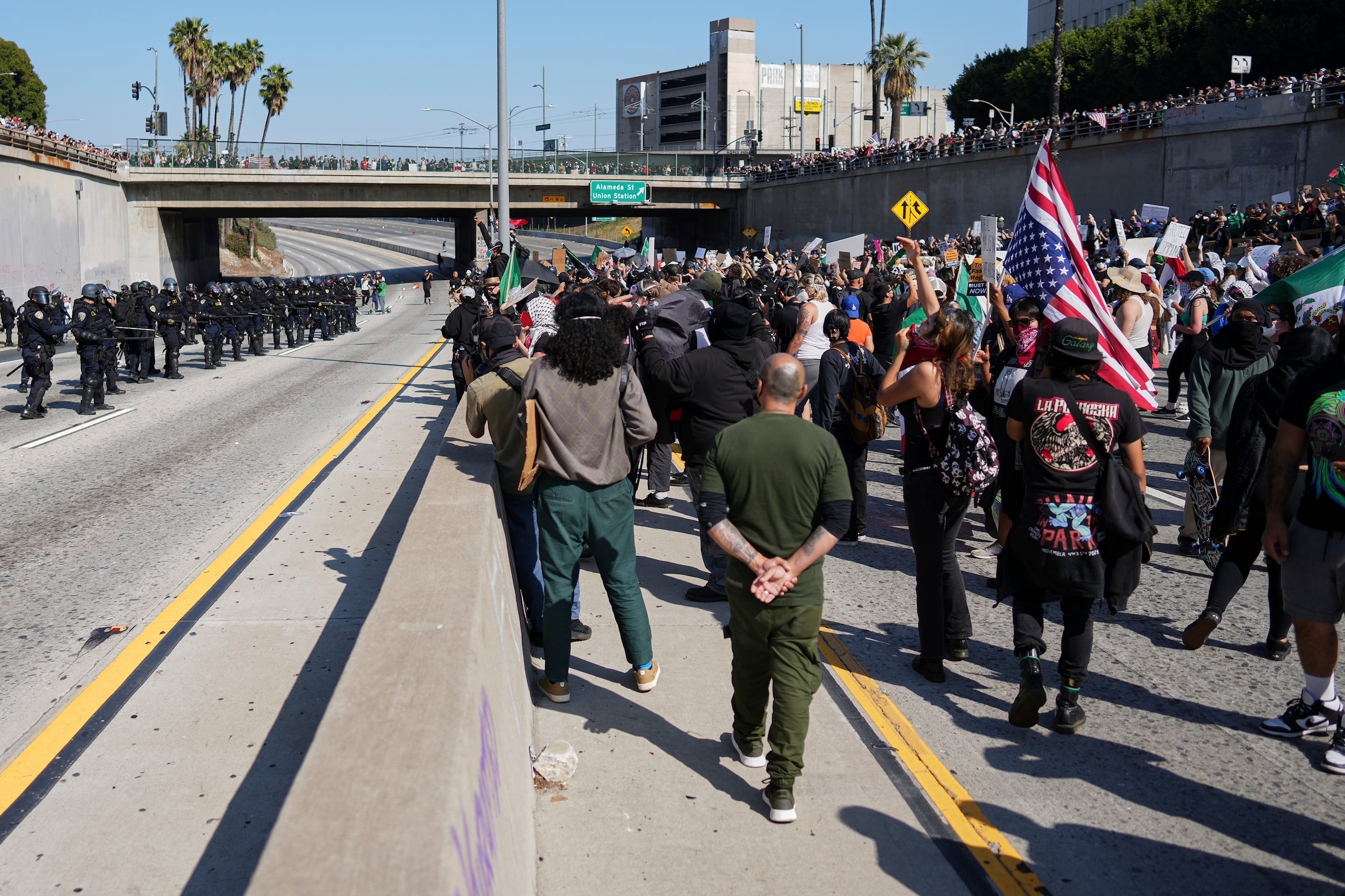 Se ve a la policía a un lado de la autopista 101 y a los manifestantes al otro, cerca del Centro de Detención Metropolitano del centro de Los Ángeles, el domingo 8 de junio de 2025, tras la redada de inmigración de anoche. (Foto AP/Eric Thayer)