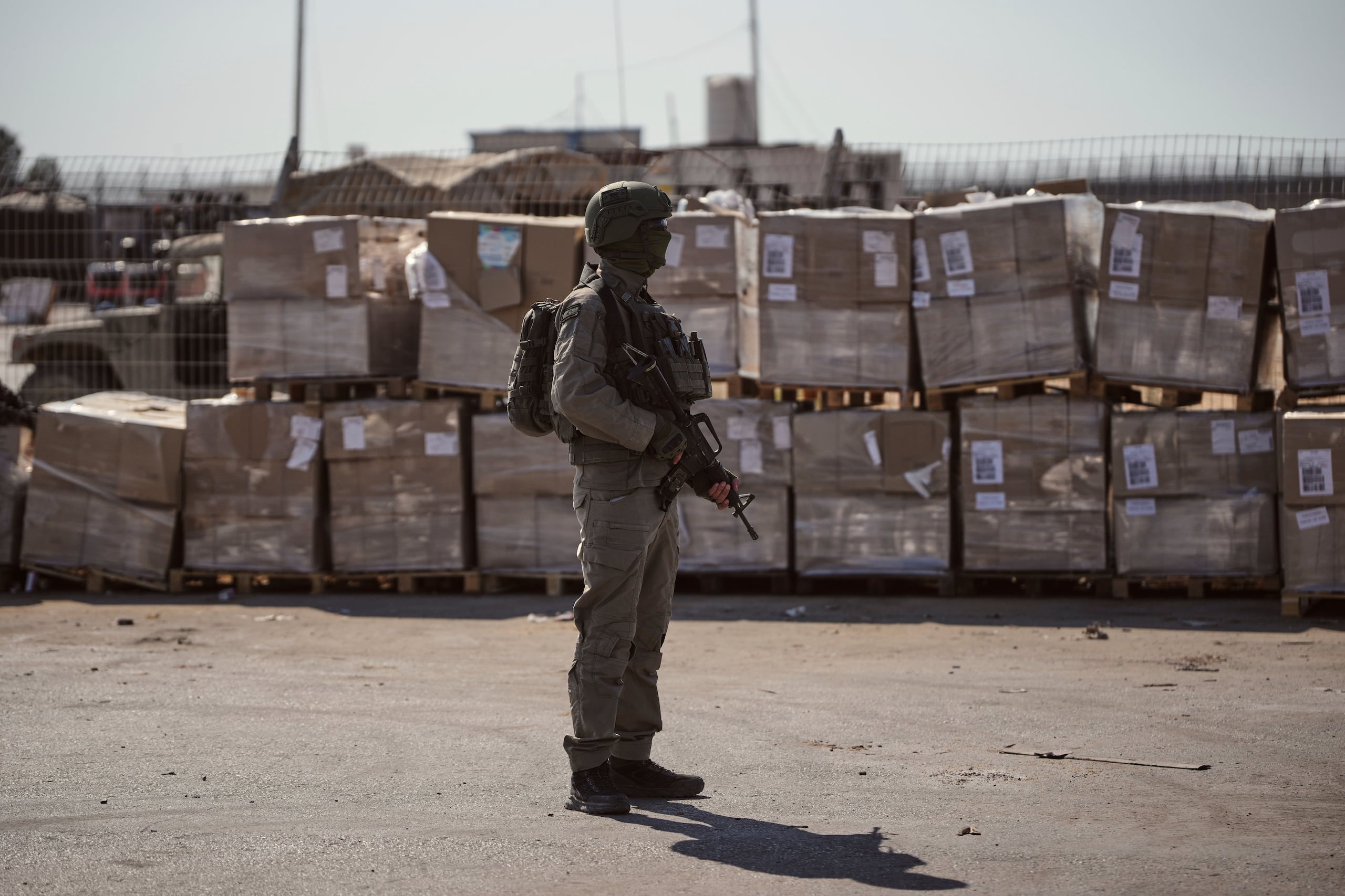 Un soldado israelí vigila paquetes de ayuda humanitaria a la espera de que sean recogidos en el lado palestino del cruce Kerem Shalom en la Franja de Gaza.