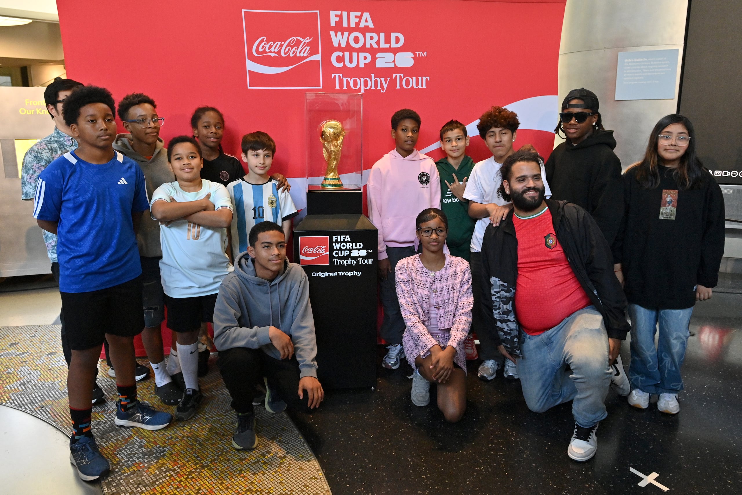 Jóvenes de los programas de City in the Community la fundación del NYCFC posan con el Trofeo de la Copa Mundial de la FIFA en el Museo Americano de Historia Natural el 2 de junio en Nueva York (EFE/The Coca Cola Company)