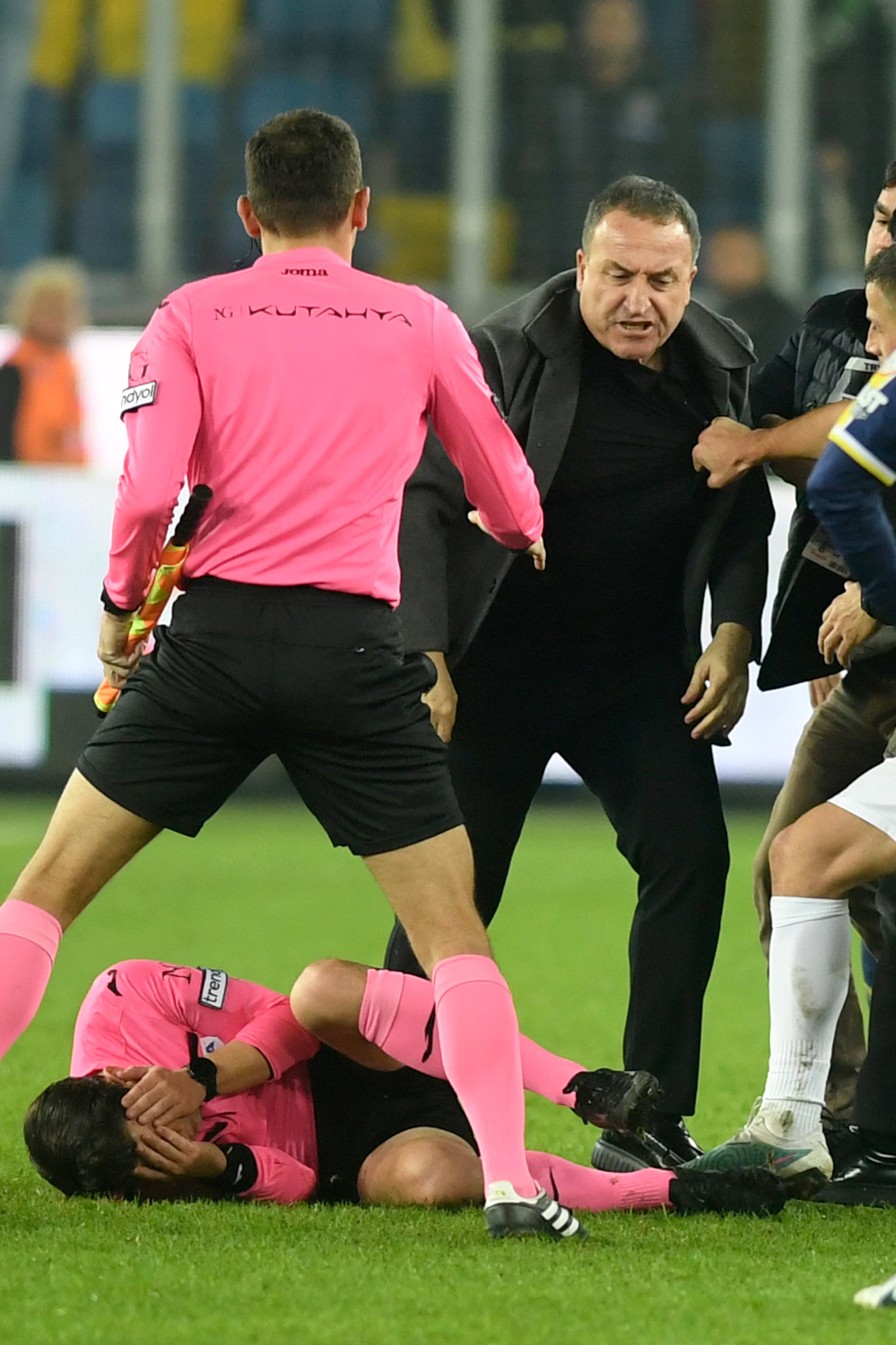 El árbitro Halil Umut Meler se toca el rostro mientras yace tendido en el césped tras ser golpeado por el presidente del MKE Ankaragucu, Faruk Koca (centro derecha), al final del partido de la Super Liga turca entre el MKE Ankaragucu y el Caykur Rizespor en Ankara, el 11 de diciembre de 2023.