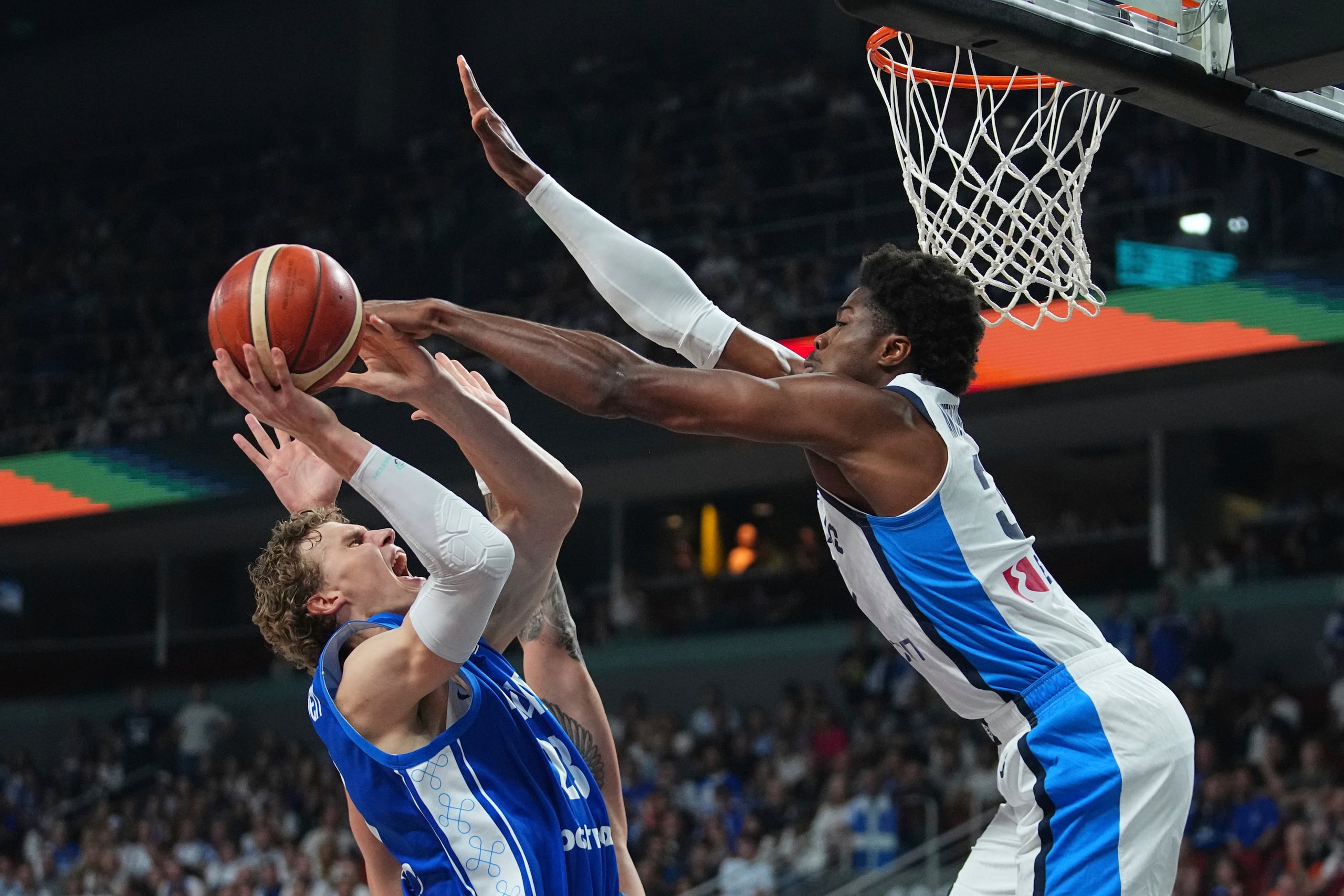 El pívot finlandés Lauri Markkanen, en el centro, intenta un lanzamiento defendido por el griego Kostas Antetokounmpo, de Grecia, durante el partido por el tercer puesto del Eurobasket.