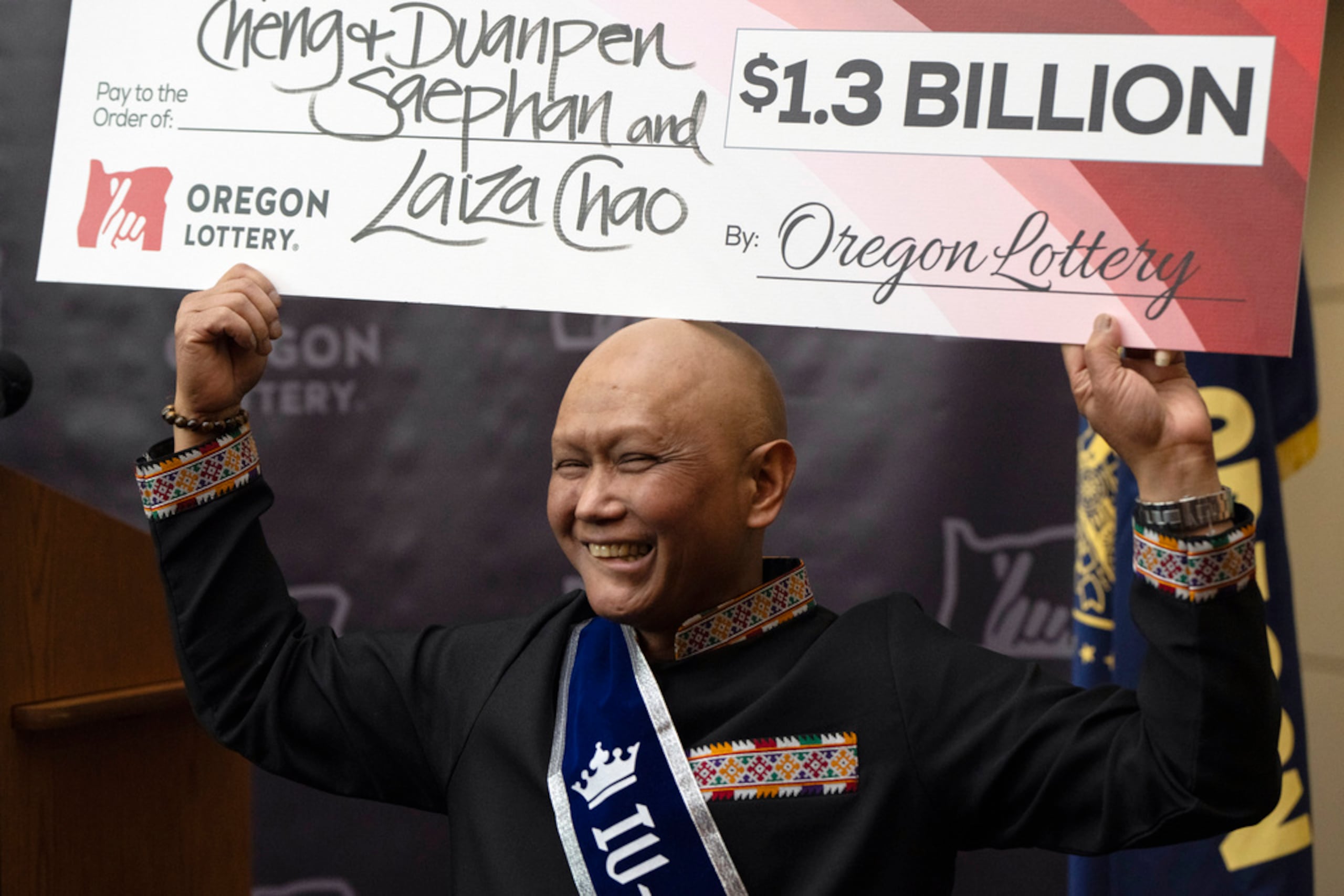 Cheng Saephan levanta un cheque después de hablar en una conferencia de prensa el 29 de abril de 2024 en las oficinas de la Lotería de Oregon, en Salem, Oregon, en la que se reveló que fue uno de los ganadores del premio de $1,300 millones de la lotería Powerball.