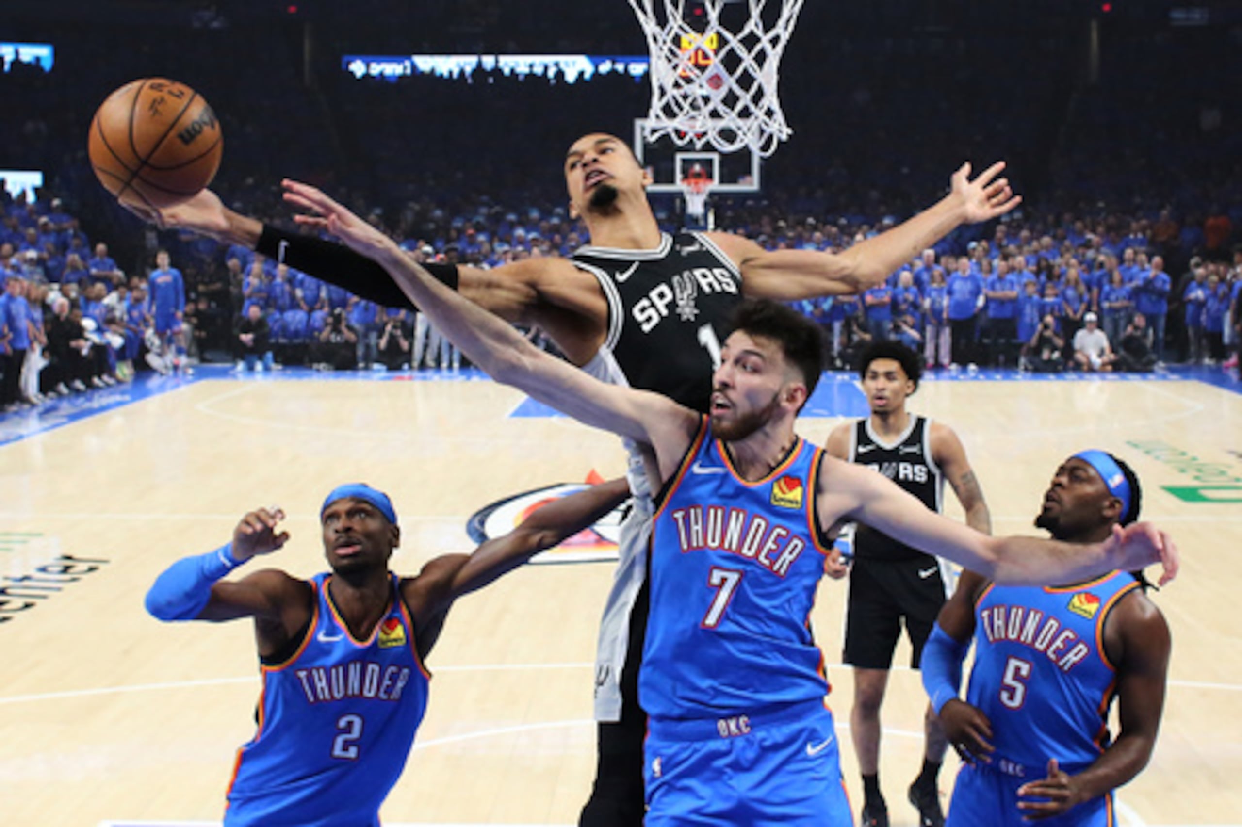 El alero de los San Antonio Spurs Victor Wembanyama (1) y el pívot de los Oklahoma City Thunder Chet Holmgren (7) buscan un rebote durante la primera mitad del primer partido de la tercera ronda de los playoffs de baloncesto de la NBA, el lunes 18 de mayo de 2026, en Oklahoma City. (AP Photo/Nate Billings)