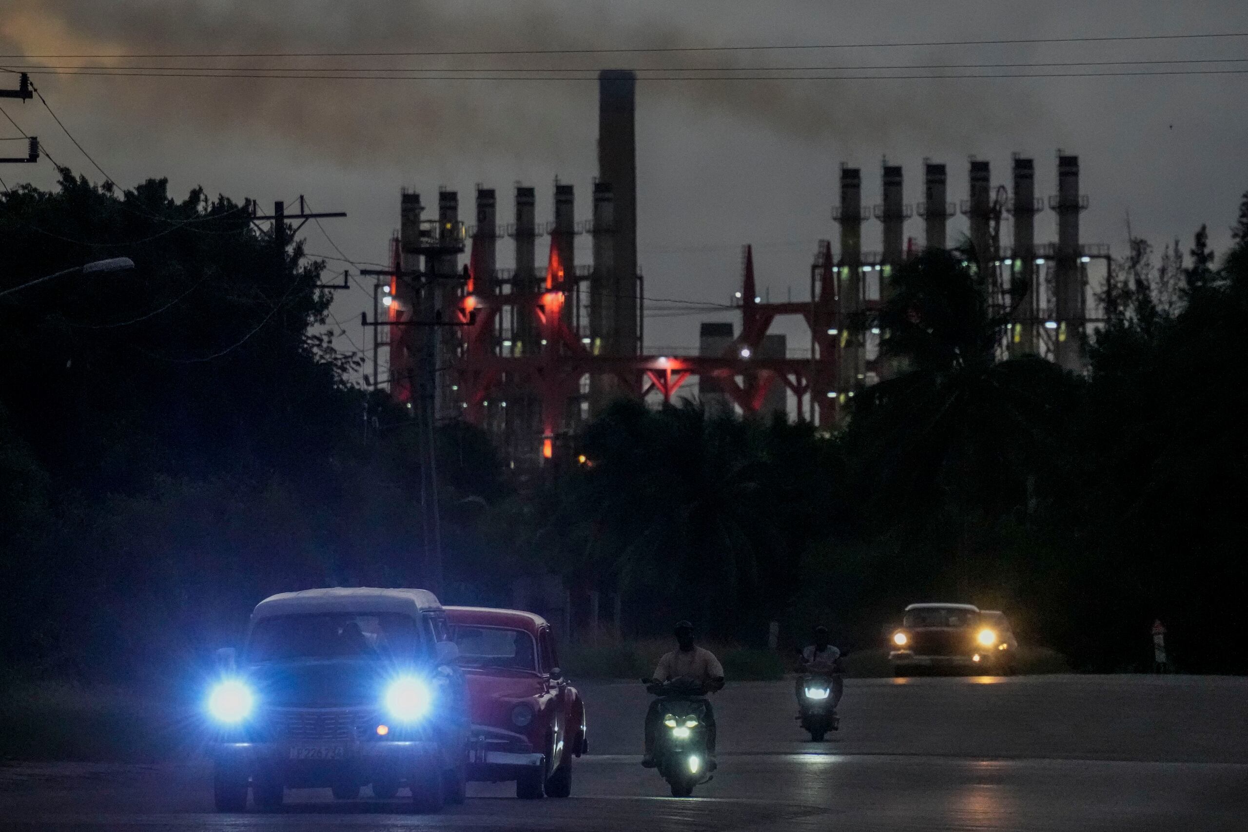 La gente conduce sus vehículos junto a un generador flotante en funcionamiento, en La Habana, Cuba, el martes 22 de octubre de 2024. (AP Foto/Ramón Espinosa)
