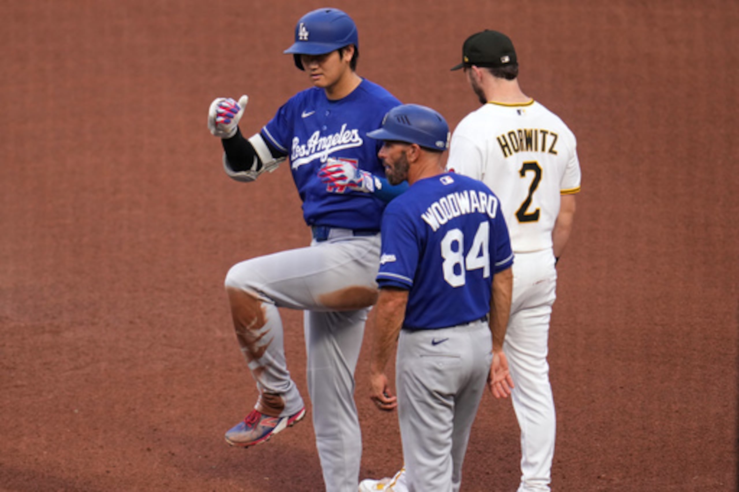 Shohei Ohtani, de los Dodgers de Los Ángeles (a la izquierda), celebra mientras se encuentra en la primera base tras batear un sencillo contra el lanzador de los Piratas de Pittsburgh, Mitch Keller, durante la cuarta entrada de un partido de béisbol disputado en Pittsburgh el jueves 11 de junio de 2026. (Foto AP/Gene J. Puskar)