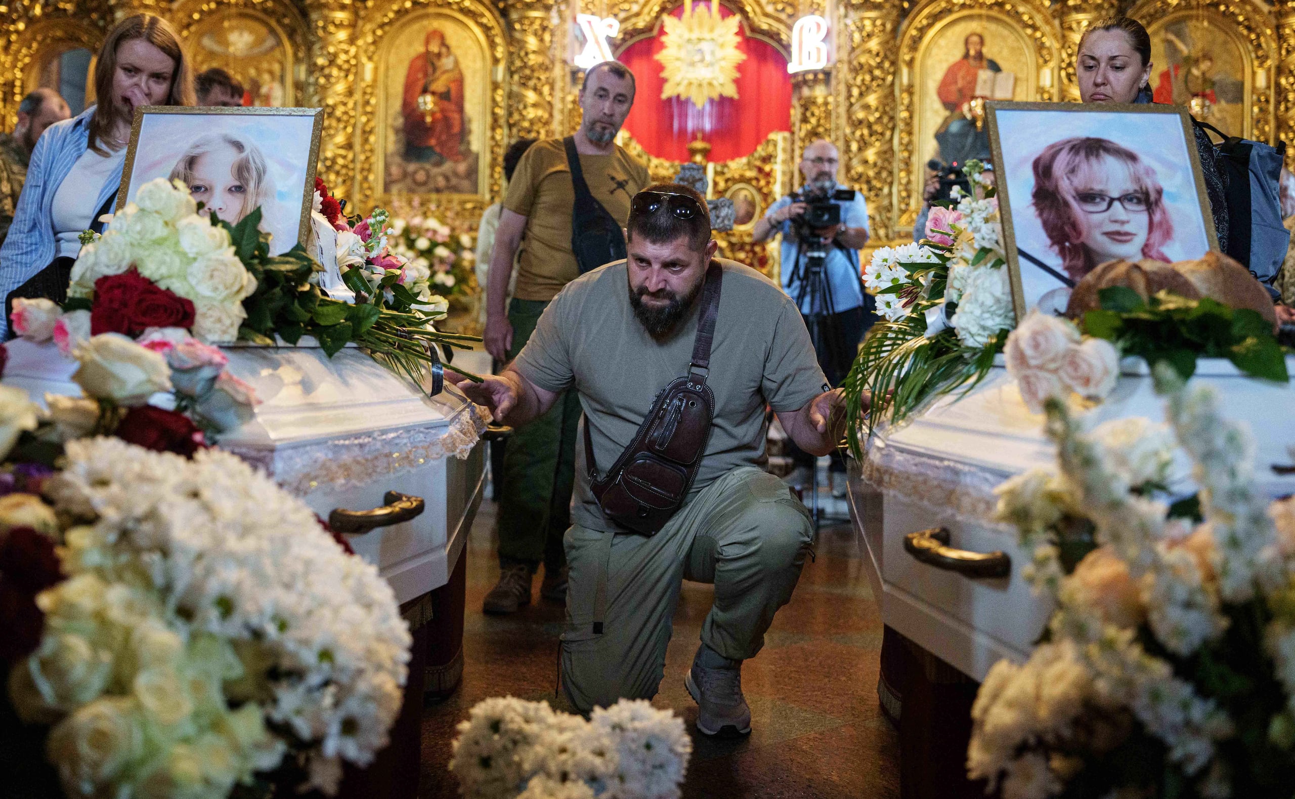 Un hombre al lado de los ataúdes de niñas muertas en un ataque ruso, en Kiev, Ucrania, el 19 de mayo del 2026. (AP foto/Evgeniy Maloletka)