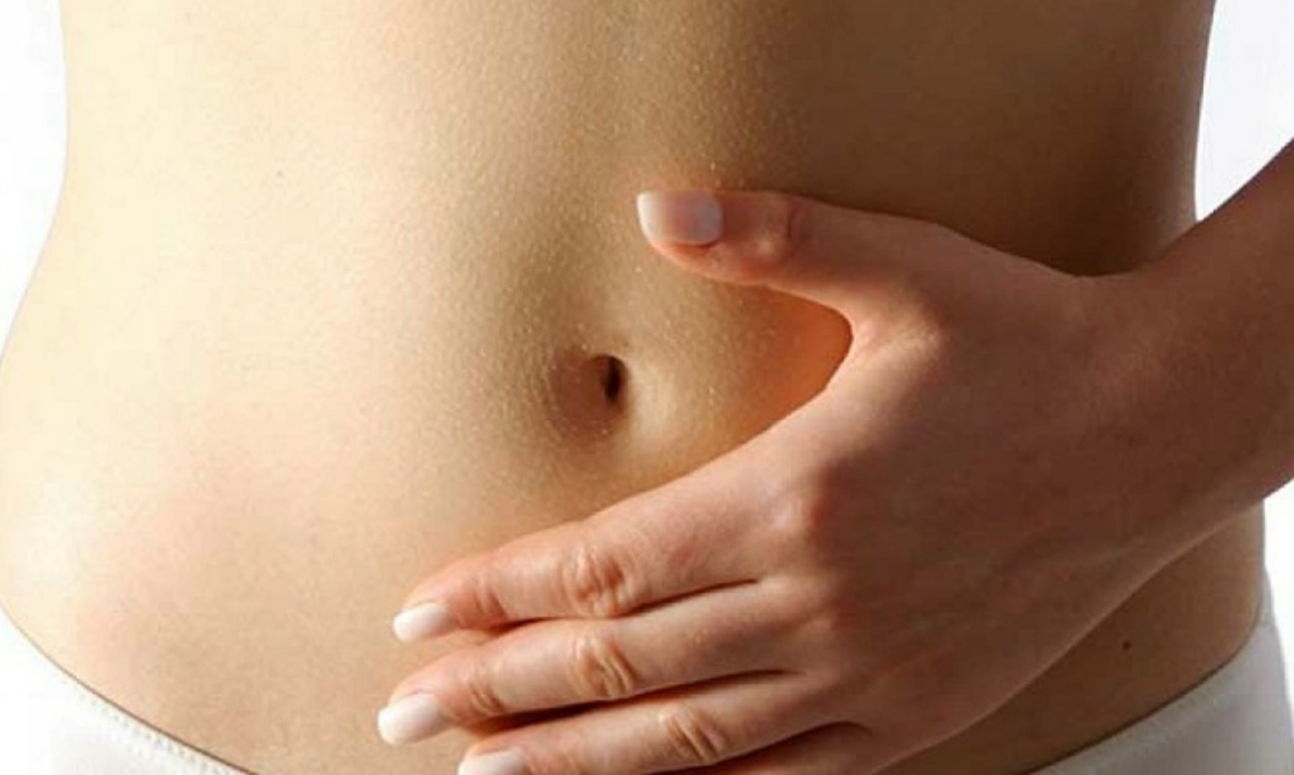 Mujer posa su mano en abdomen bajo.