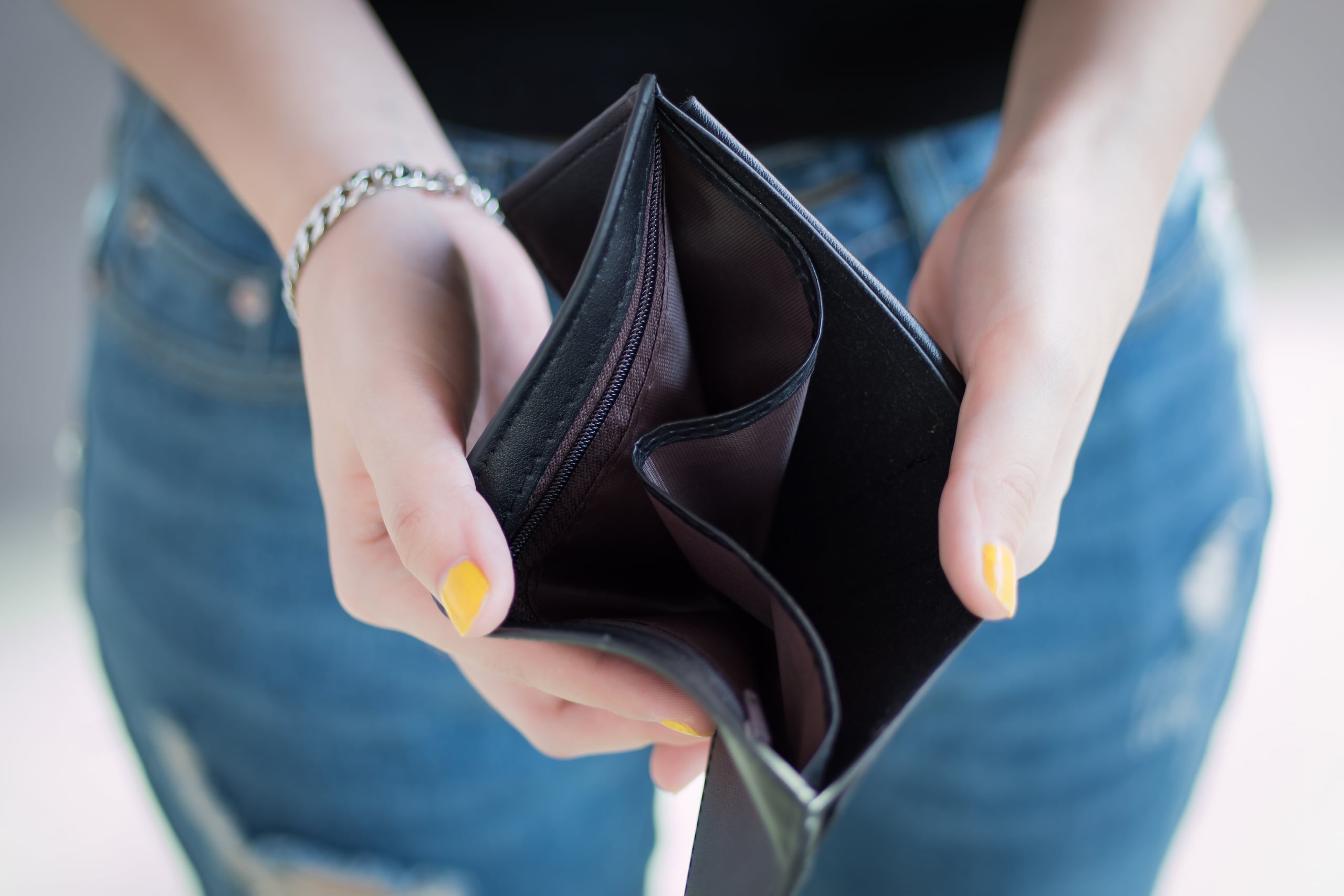 Una mujer muestra su cartera vacía