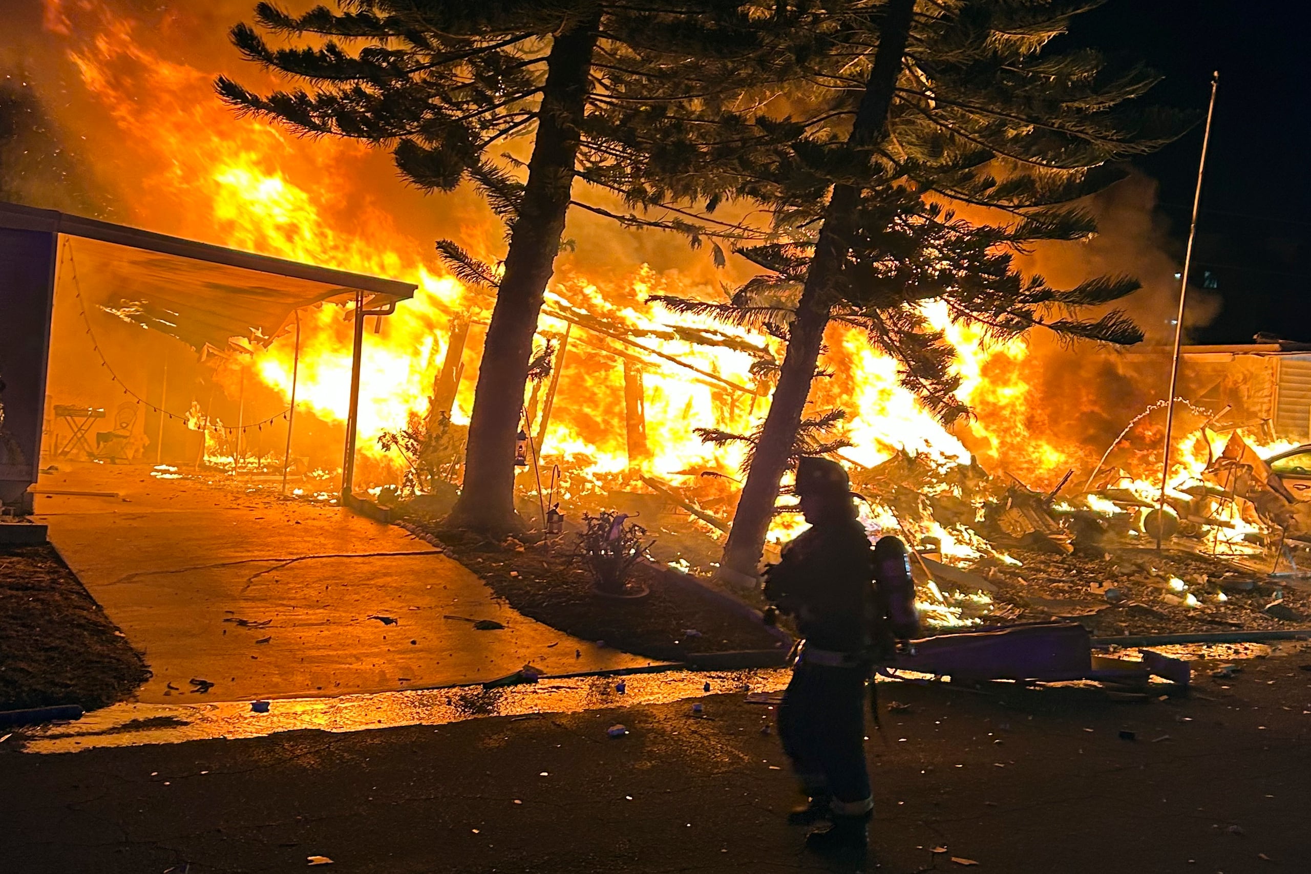 Bomberos combaten el fuego en la casa rodante que fue impactada por la avioneta.