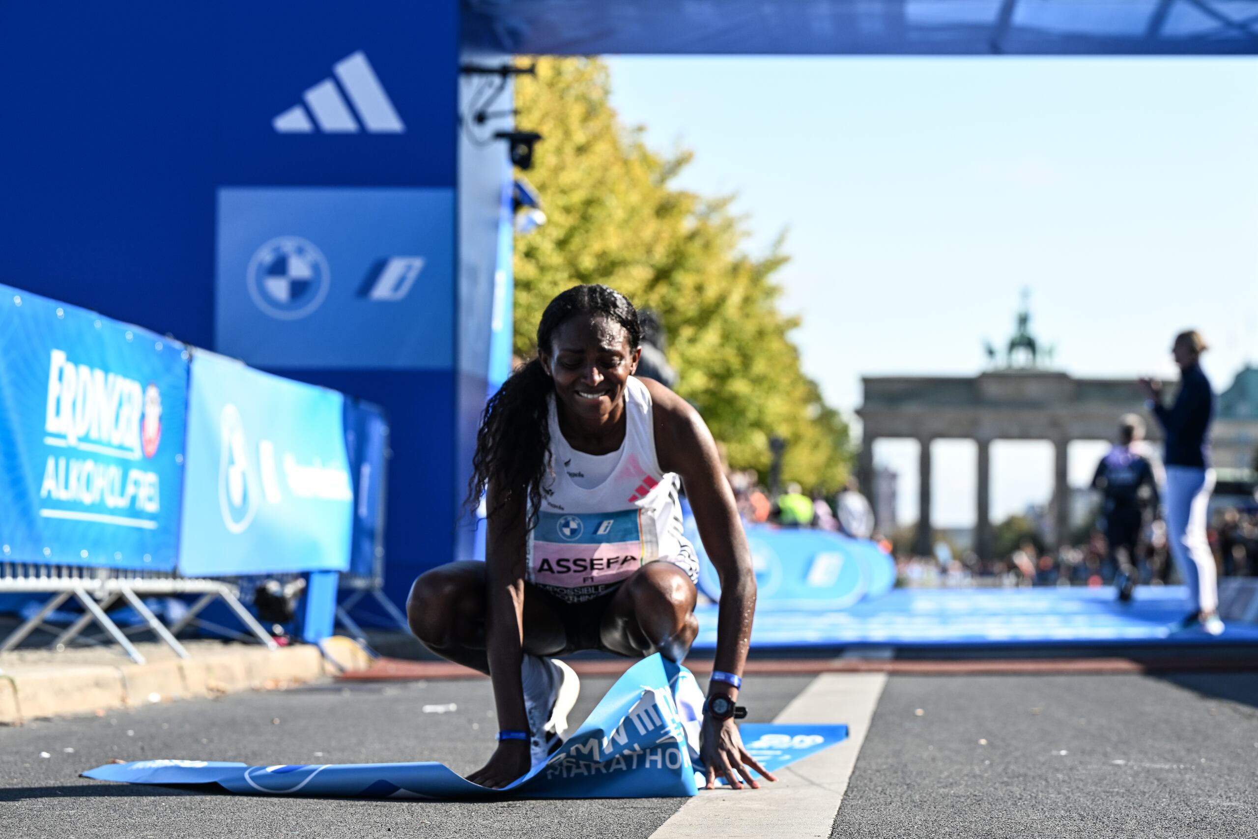 La etíope Tigist Assefa, ganadora del Maratón de Berlín, se arrodilla luego de cruzar la meta con una nueva marca mundial para la distancia larga.