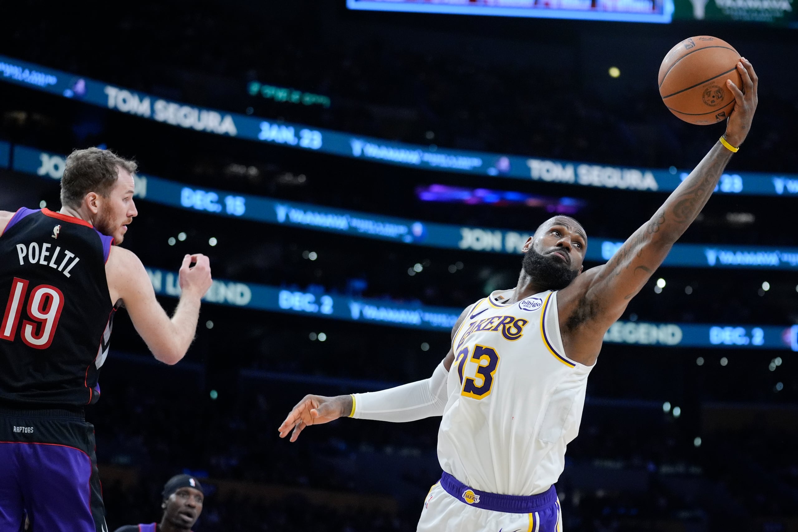El alero de los Lakers de Los Ángeles, LeBron James, recupera un rebote frente al pívot de los Raptors de Toronto, Jakob Poeltl, en el encuentro del domingo 10 de noviembre del 2024.