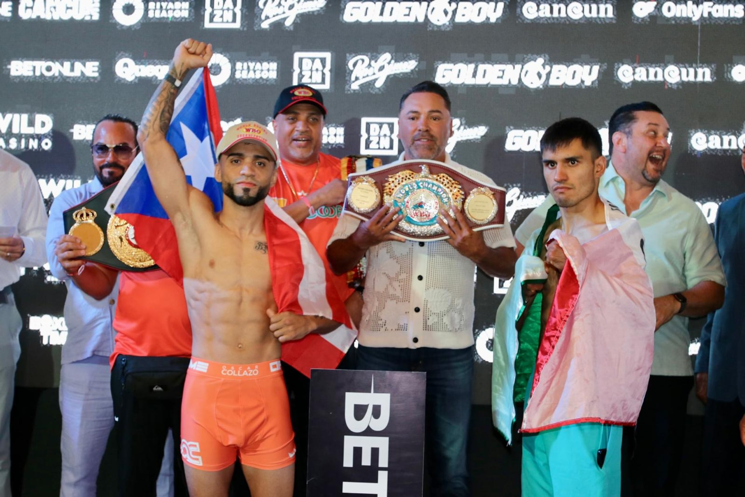 El campeón mundial de las 105 libras, el boricua Oscar Collazo, levanta su puño tras el pesaje para su combate ante el mexicano Edwin "Canito" Cano Hernández (derecha). Al centro, Oscar de la Hoya, promotor de la cartelera en Cancún.
